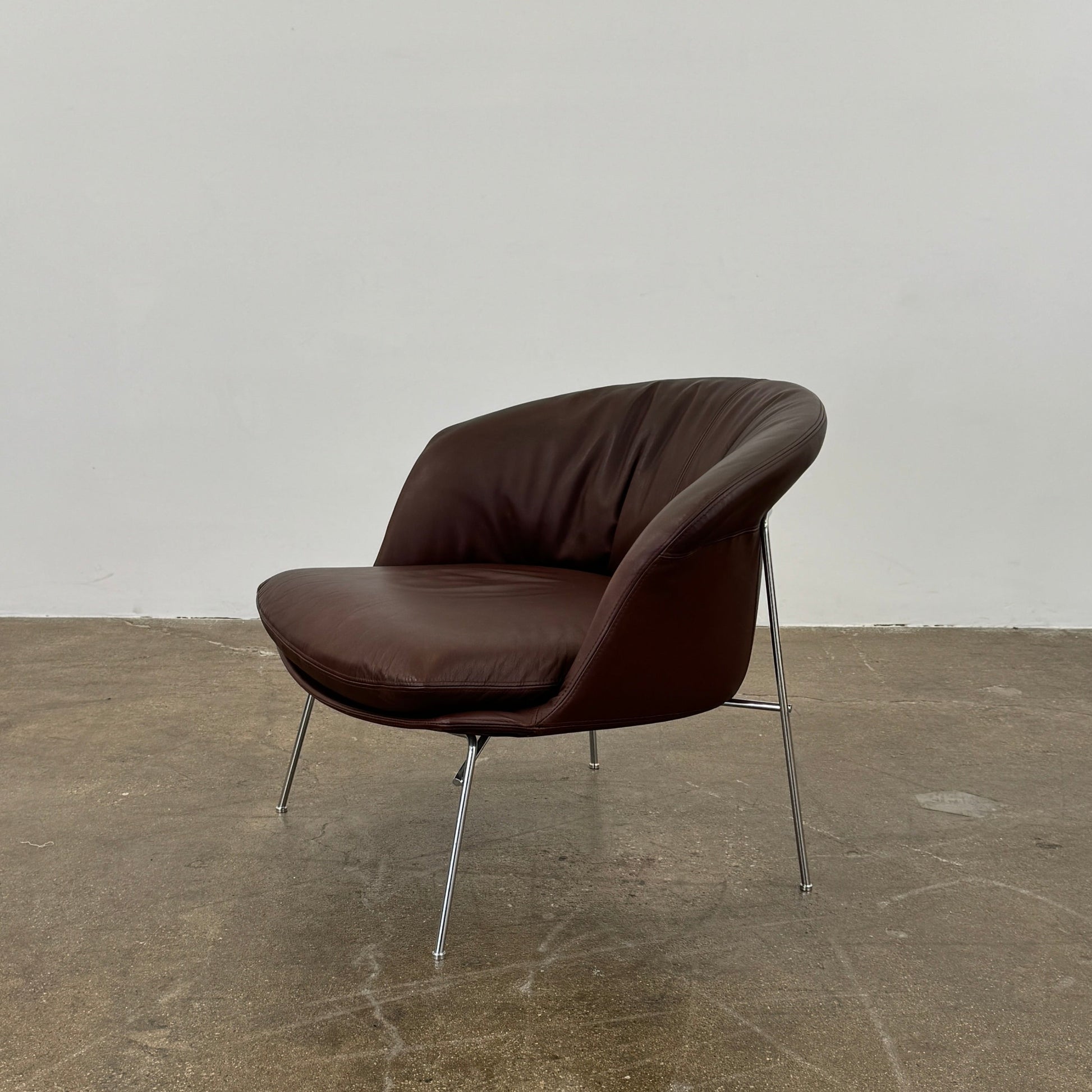 The Driade Moon Lounge Chair by Driade features a modern brown leather design, curved backrest, and slim metal legs, shown against a plain white background.