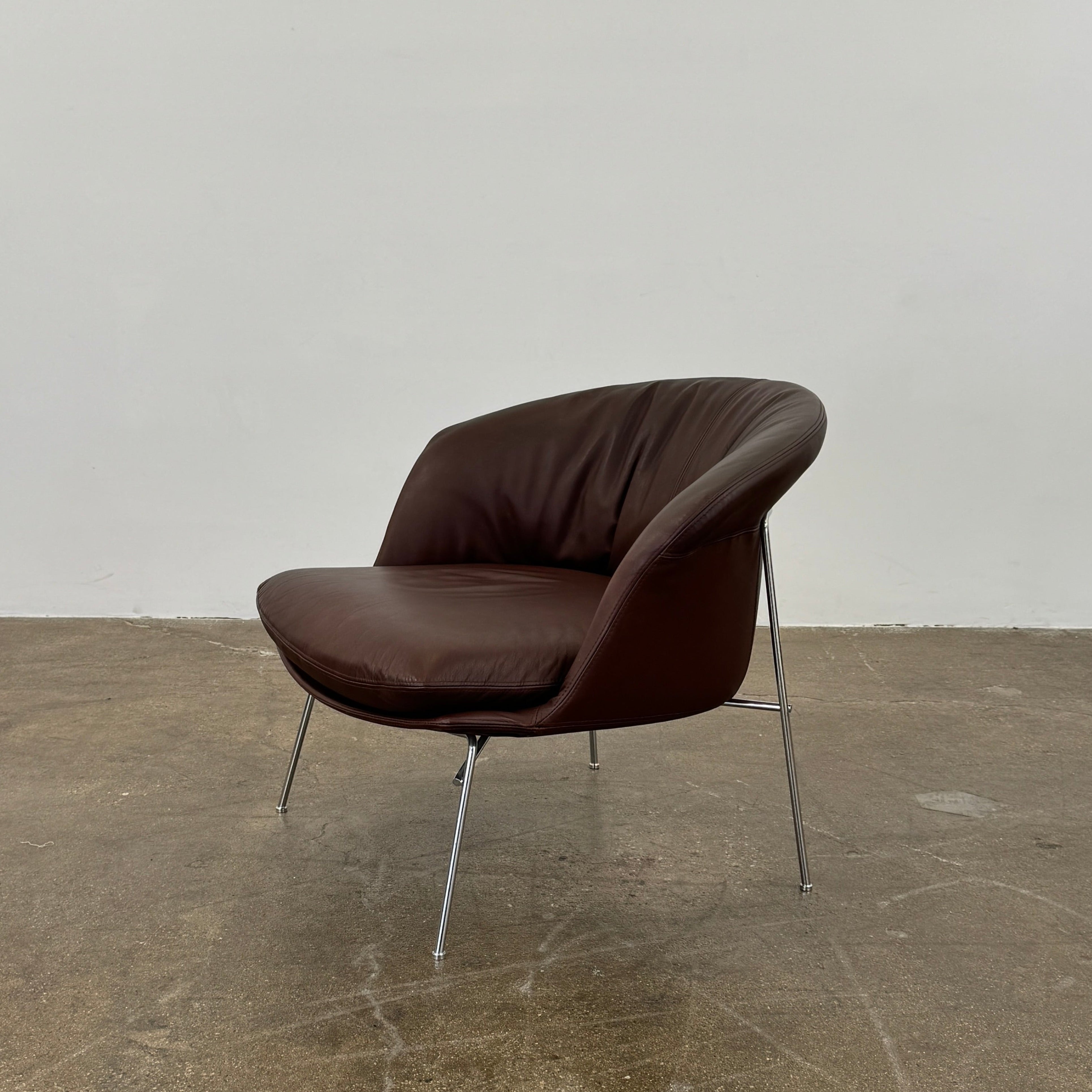 The Driade Moon Lounge Chair by Driade features a modern brown leather design, curved backrest, and slim metal legs, shown against a plain white background.