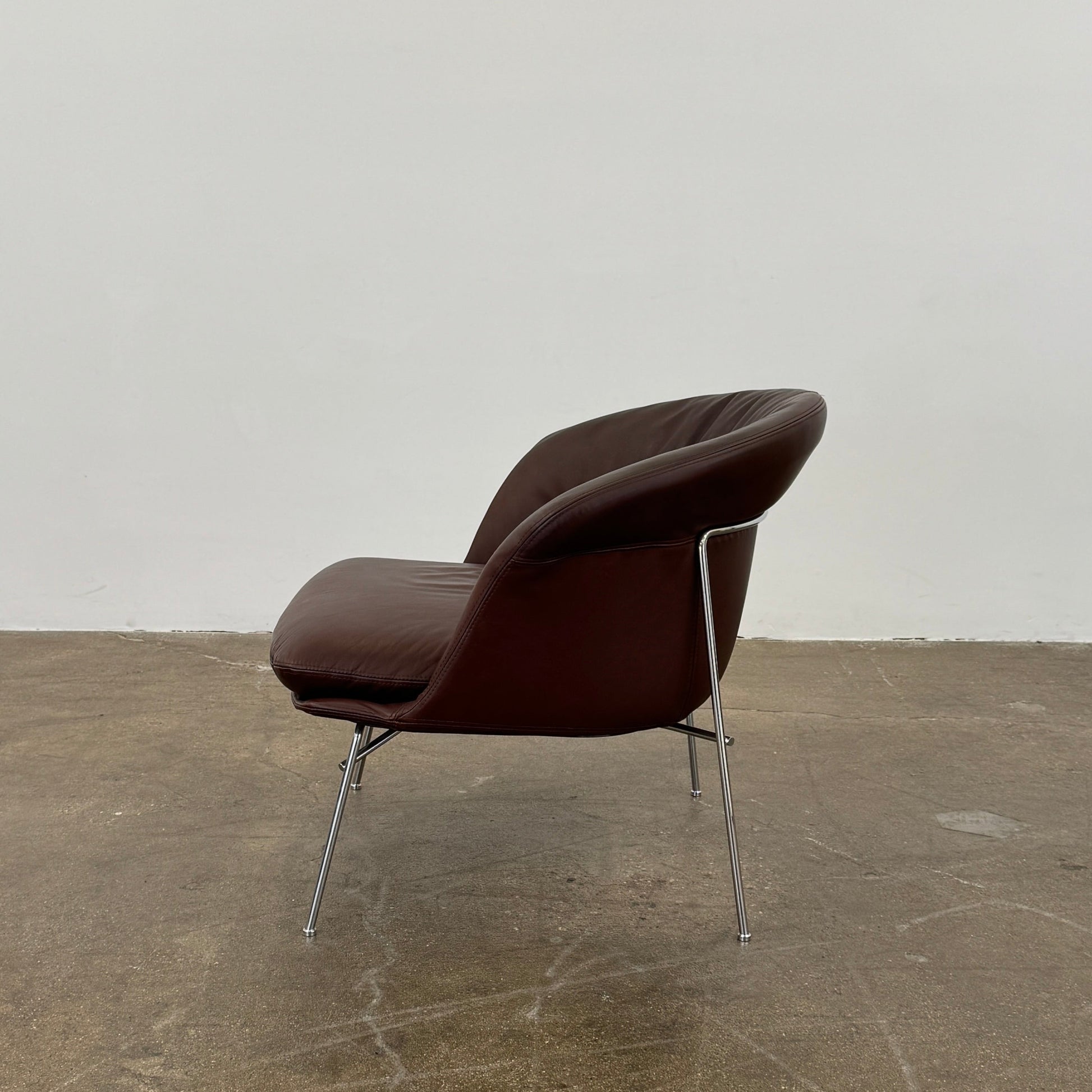 The Driade Moon Lounge Chair by Driade features a modern brown leather design, curved backrest, and slim metal legs, shown against a plain white background.
