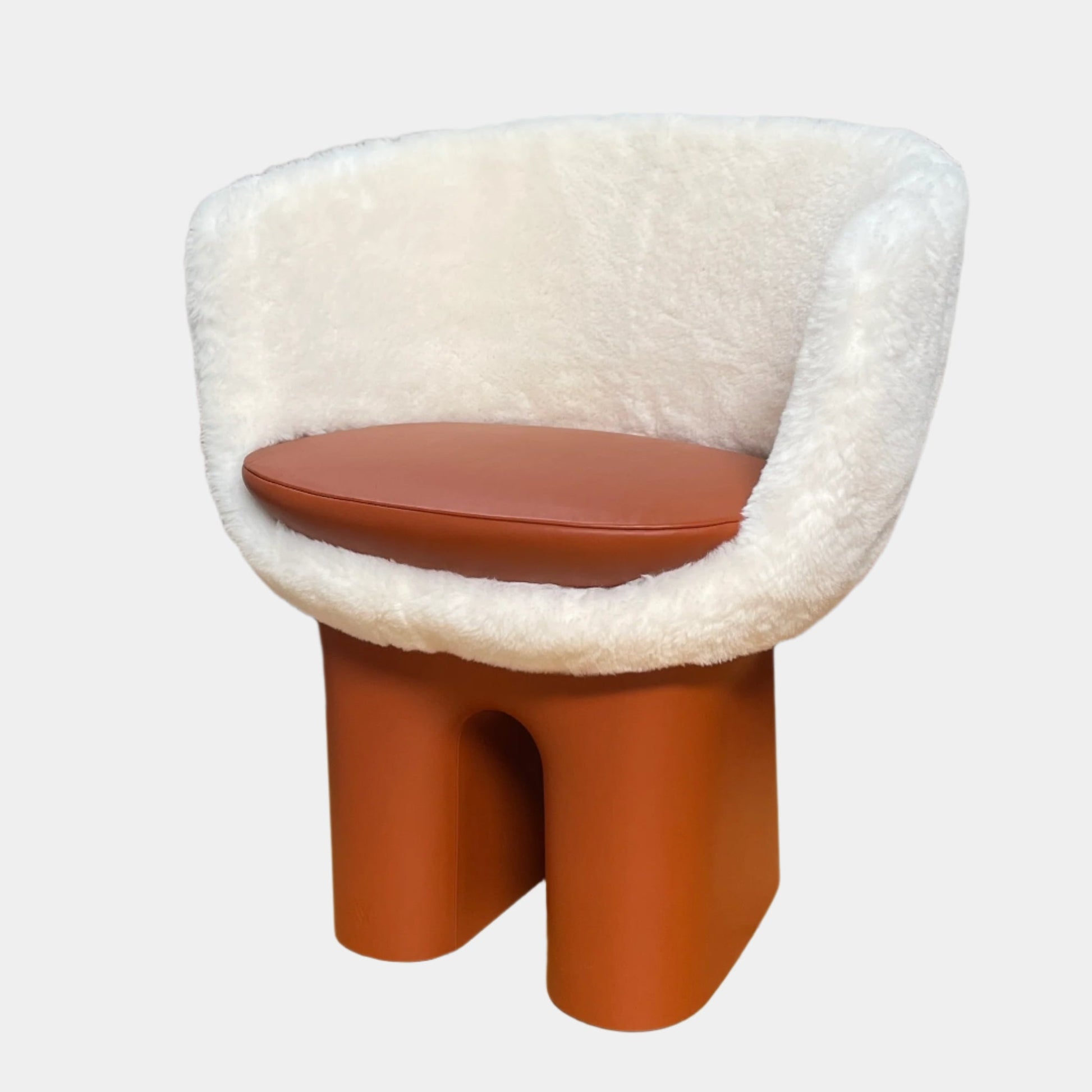 The Louis Vuitton Dolls Fur by Raw Edges is a modern chair with a curved white fluffy leather and fur seat, two short cylindrical brown legs, and a matching brown base, designed by Louis Vuitton and set against a plain background.
