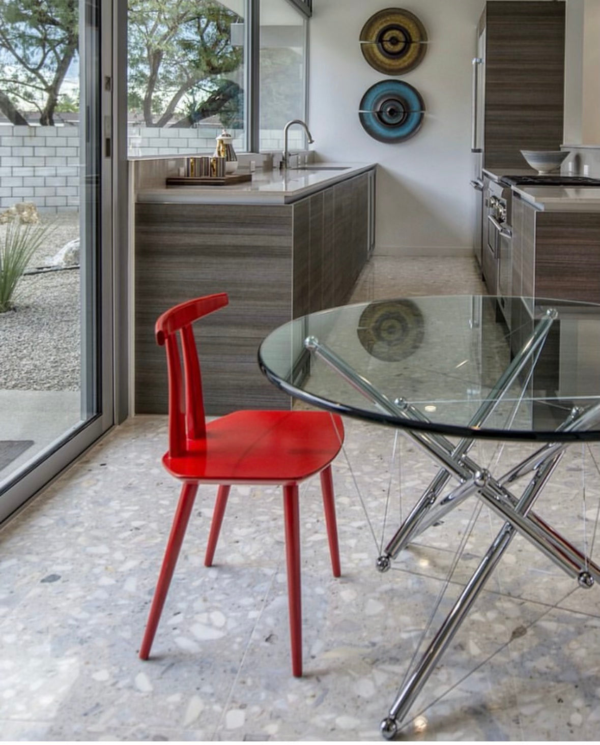 The Torii Chair by Bensen features a minimalist design with a round backrest and angled legs, crafted in red wood. Shown against a plain light background, this piece showcases Bensen's signature style.