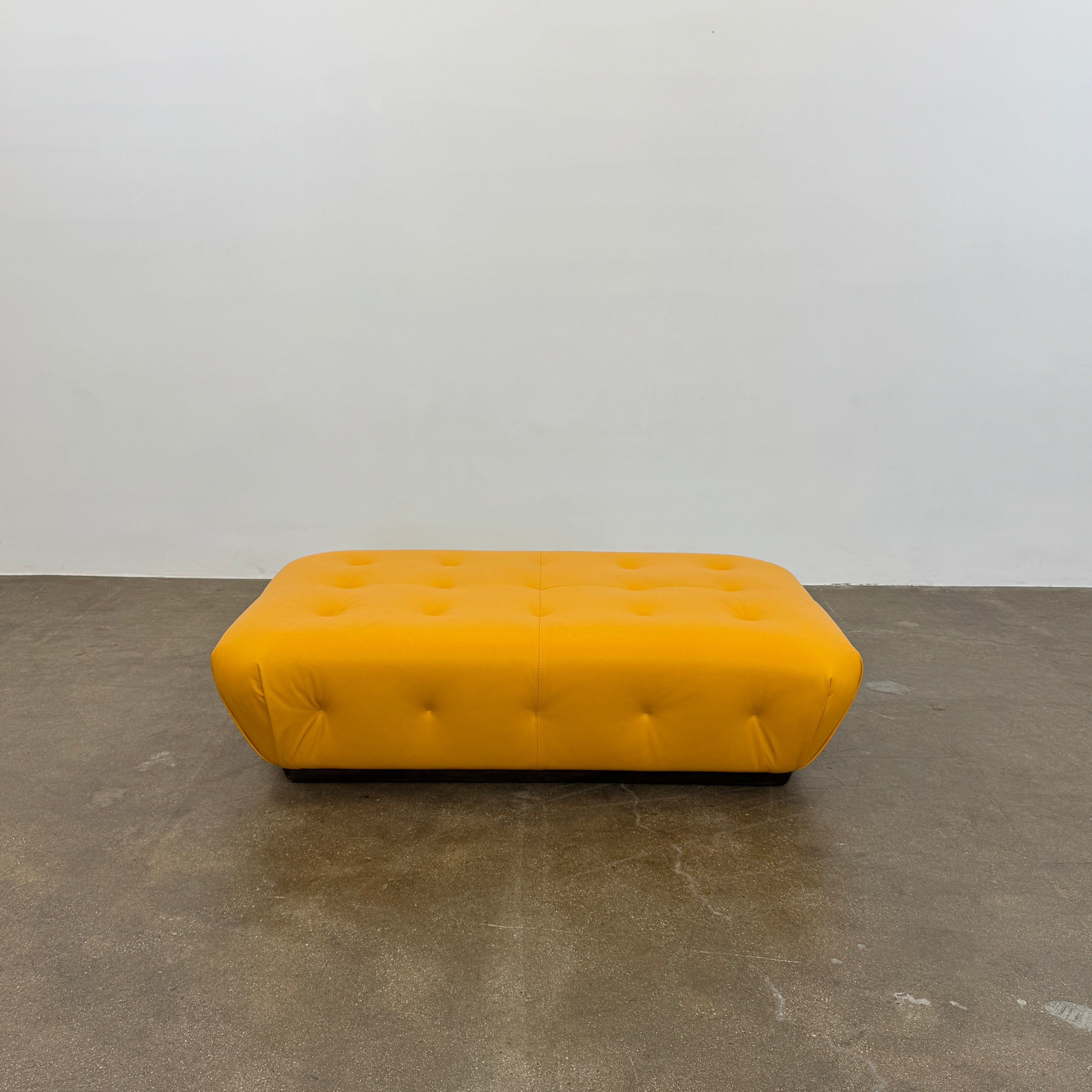 Yellow rectangular Tufted Leather Ottoman with rounded edges and a flat black base, ideal for extra seating, displayed on a plain white background. Brand: Unknown.