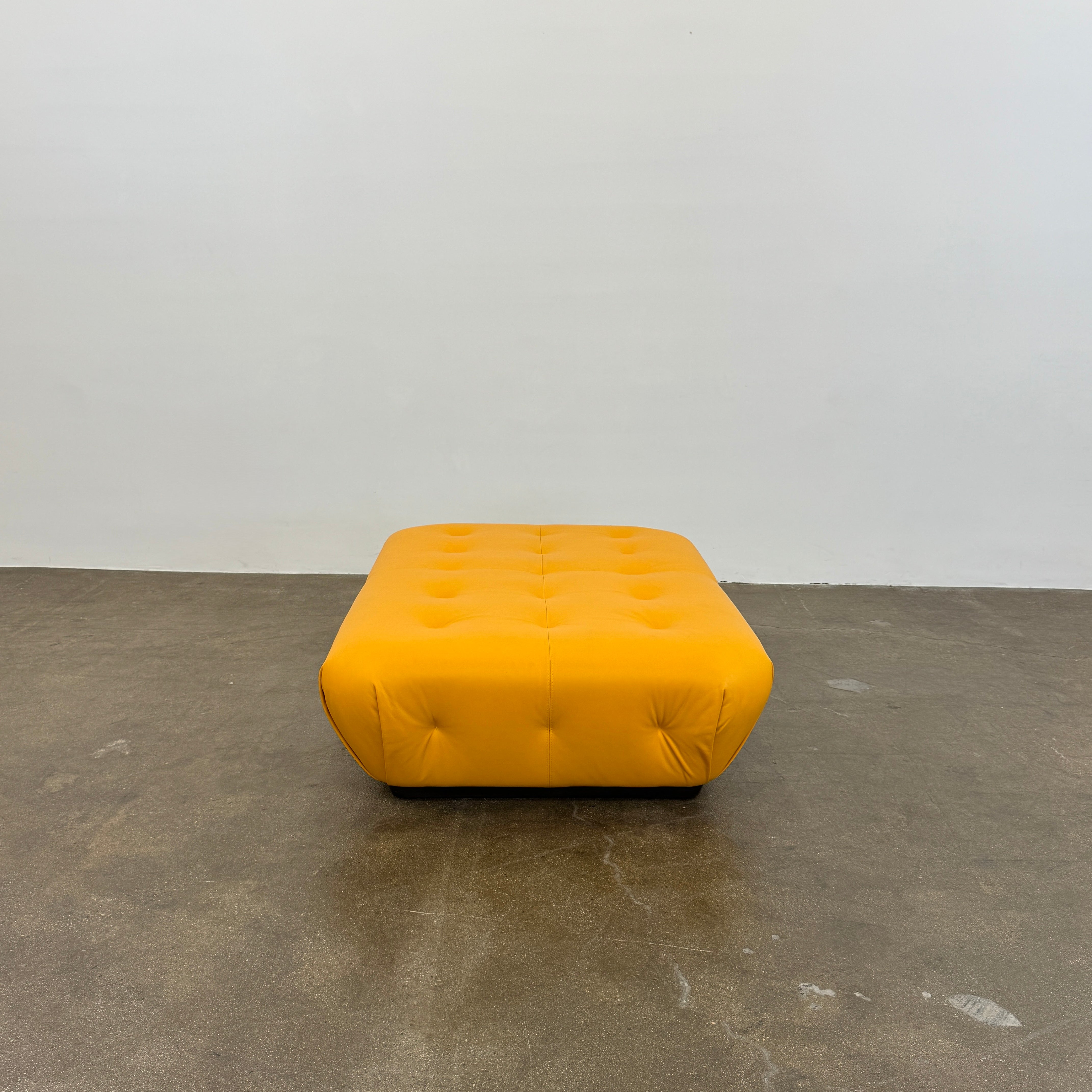 Yellow rectangular Tufted Leather Ottoman with rounded edges and a flat black base, ideal for extra seating, displayed on a plain white background. Brand: Unknown.