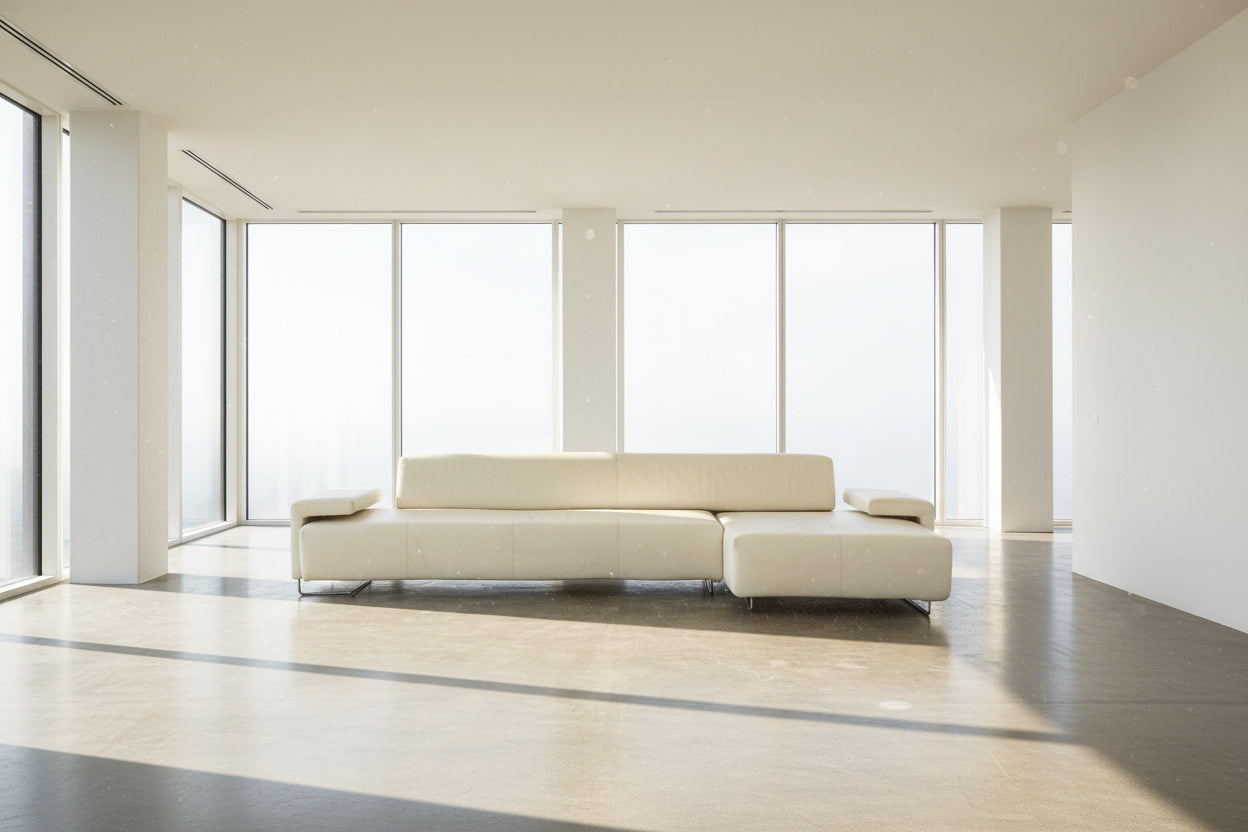 A Moroso Lowland Sectional Sofa in bone leather, with a right chaise lounge, stands on a bare concrete floor against a plain light wall.