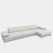 A Moroso Lowland Sectional Sofa in bone leather, with a right chaise lounge, stands on a bare concrete floor against a plain light wall.