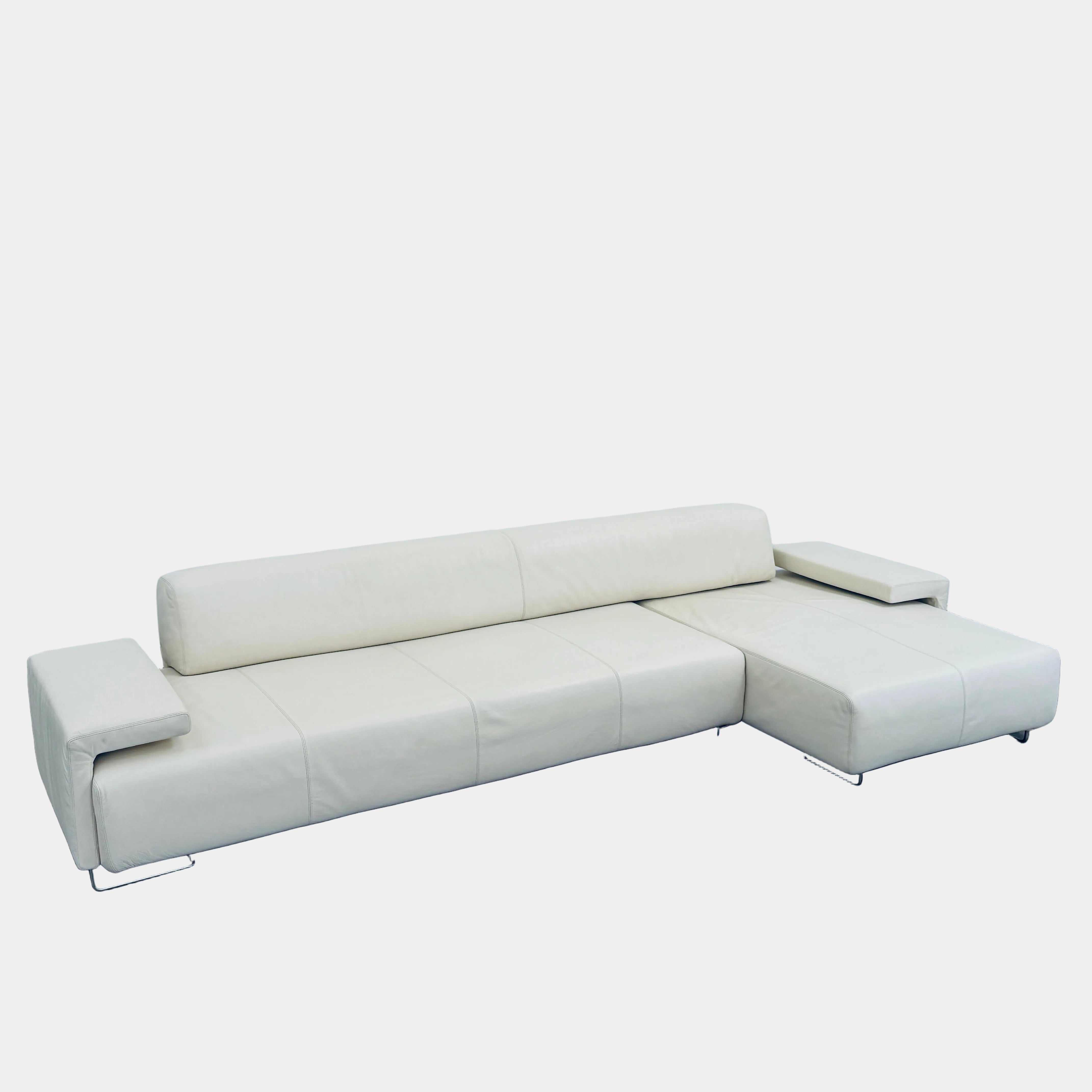 A Moroso Lowland Sectional Sofa in bone leather, with a right chaise lounge, stands on a bare concrete floor against a plain light wall.