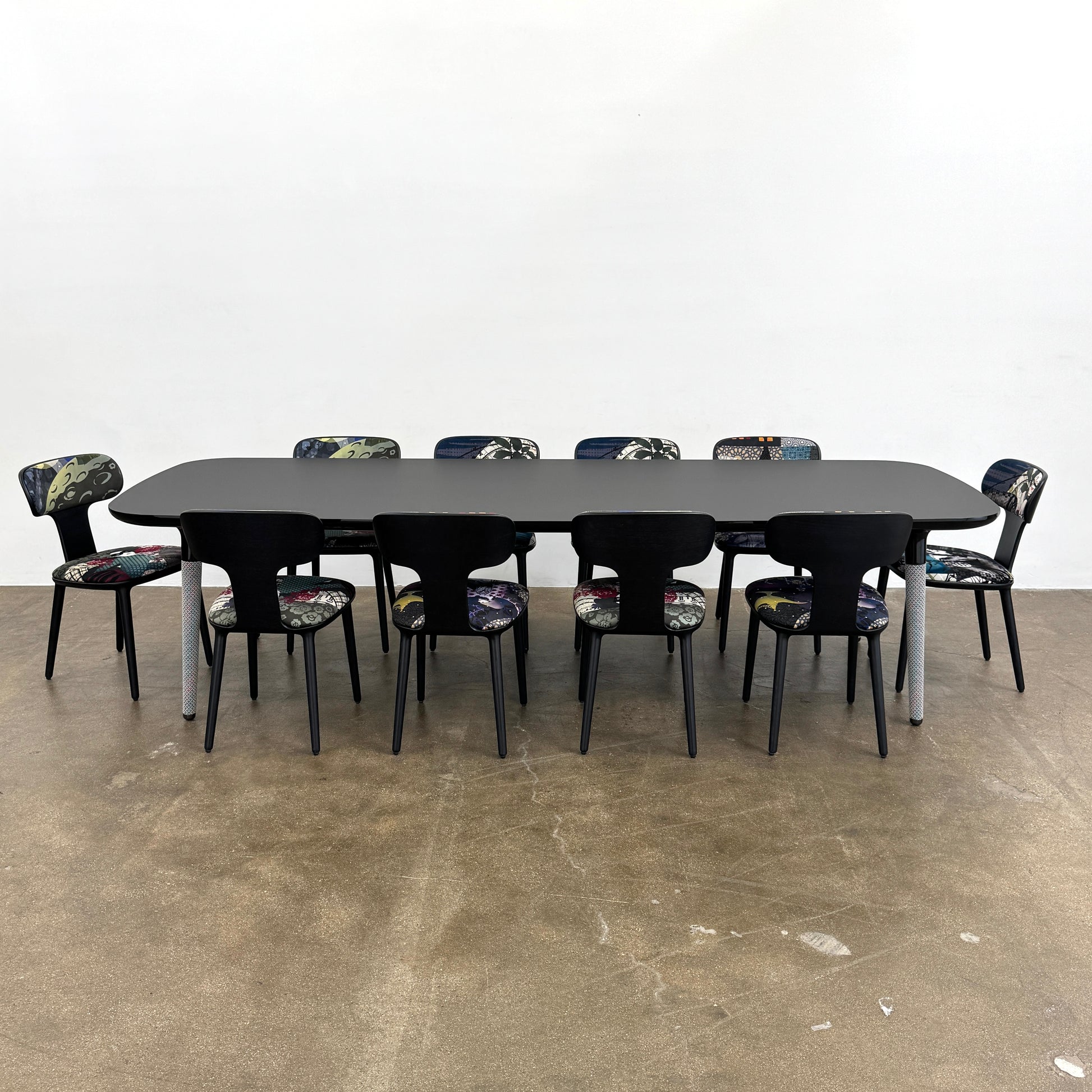 A set of six black Roche Bobois Globe Trotter Operette dining chairs, featuring patterned cushions and backs, arranged in two rows against a plain white background.