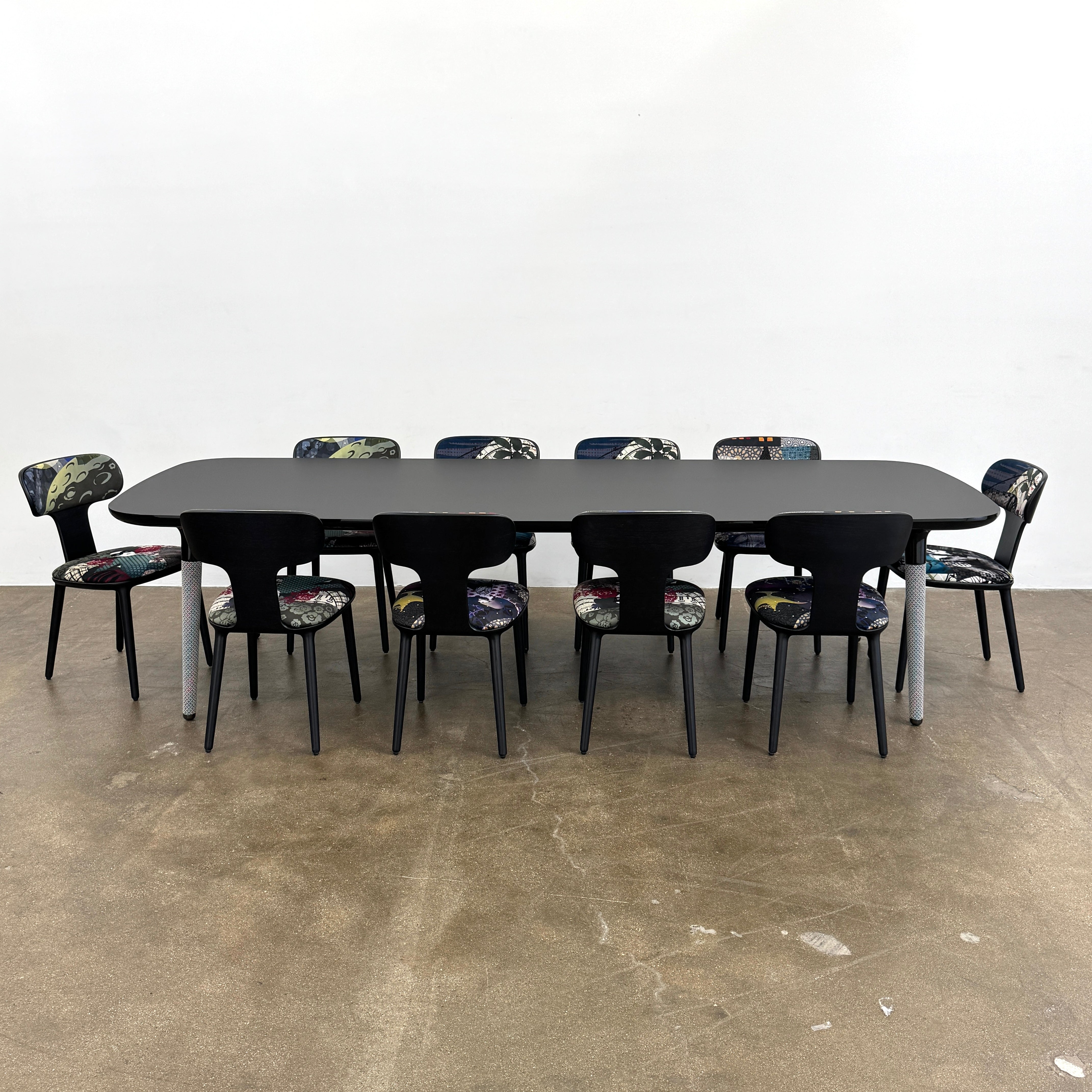 A set of six black Roche Bobois Globe Trotter Operette dining chairs, featuring patterned cushions and backs, arranged in two rows against a plain white background.