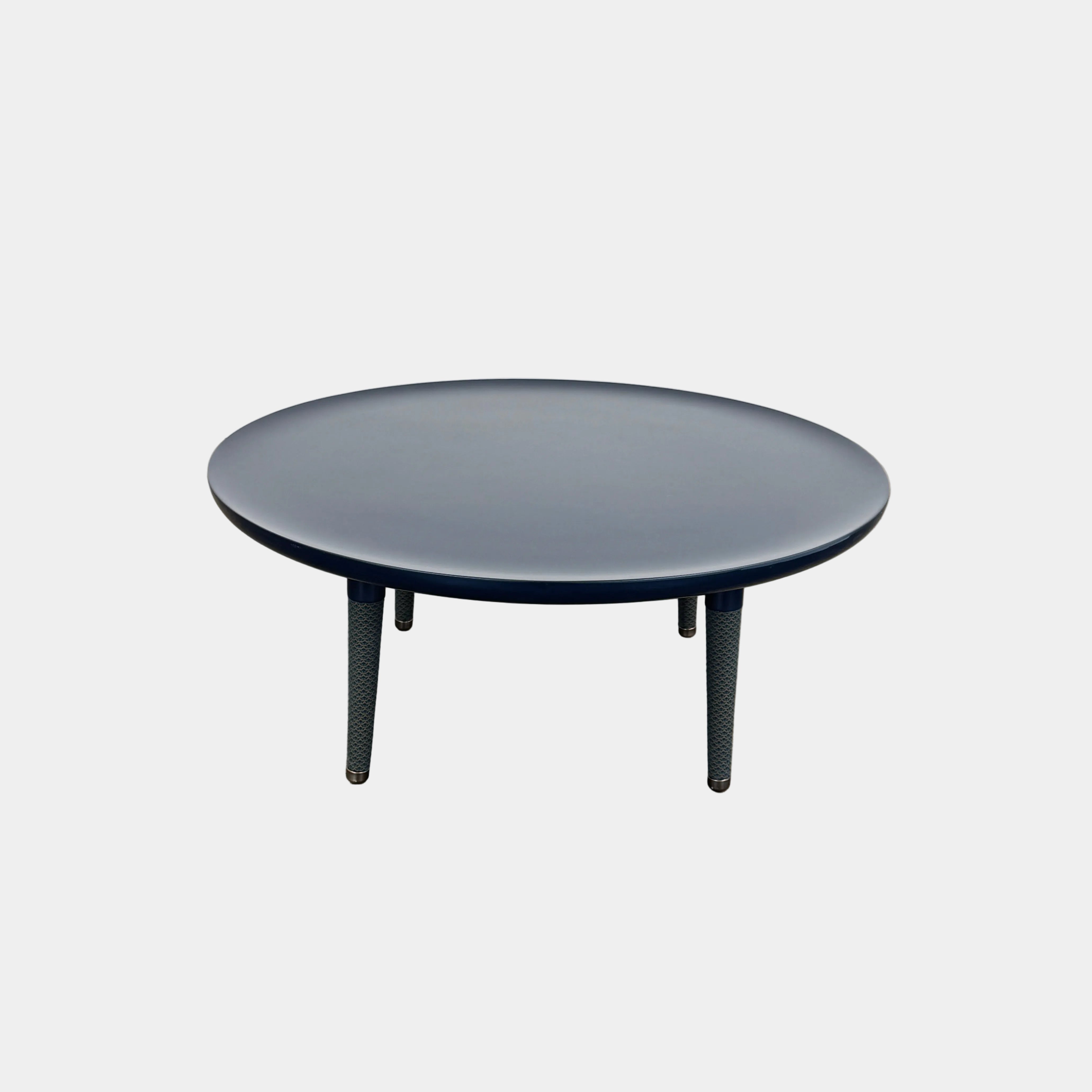 The Roche Bobois Globe Trotter La Parisienne cocktail table features a round, dark blue top and three textured legs, shown against a light gray background.