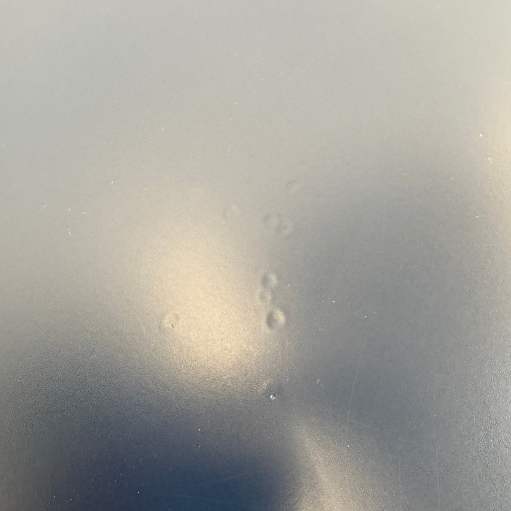 The Roche Bobois Globe Trotter La Parisienne cocktail table features a round, dark blue top and three textured legs, shown against a light gray background.