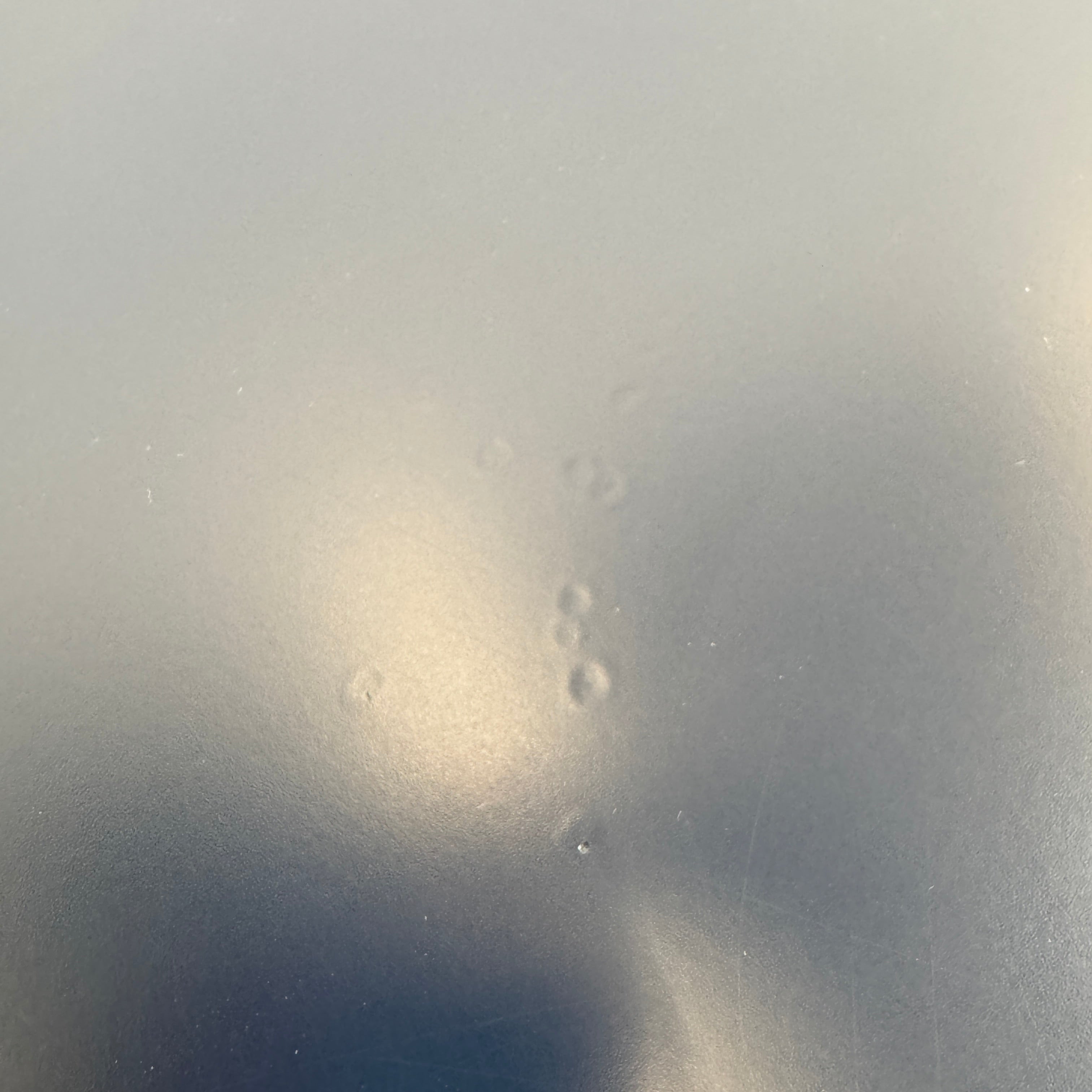 The Roche Bobois Globe Trotter La Parisienne cocktail table features a round, dark blue top and three textured legs, shown against a light gray background.