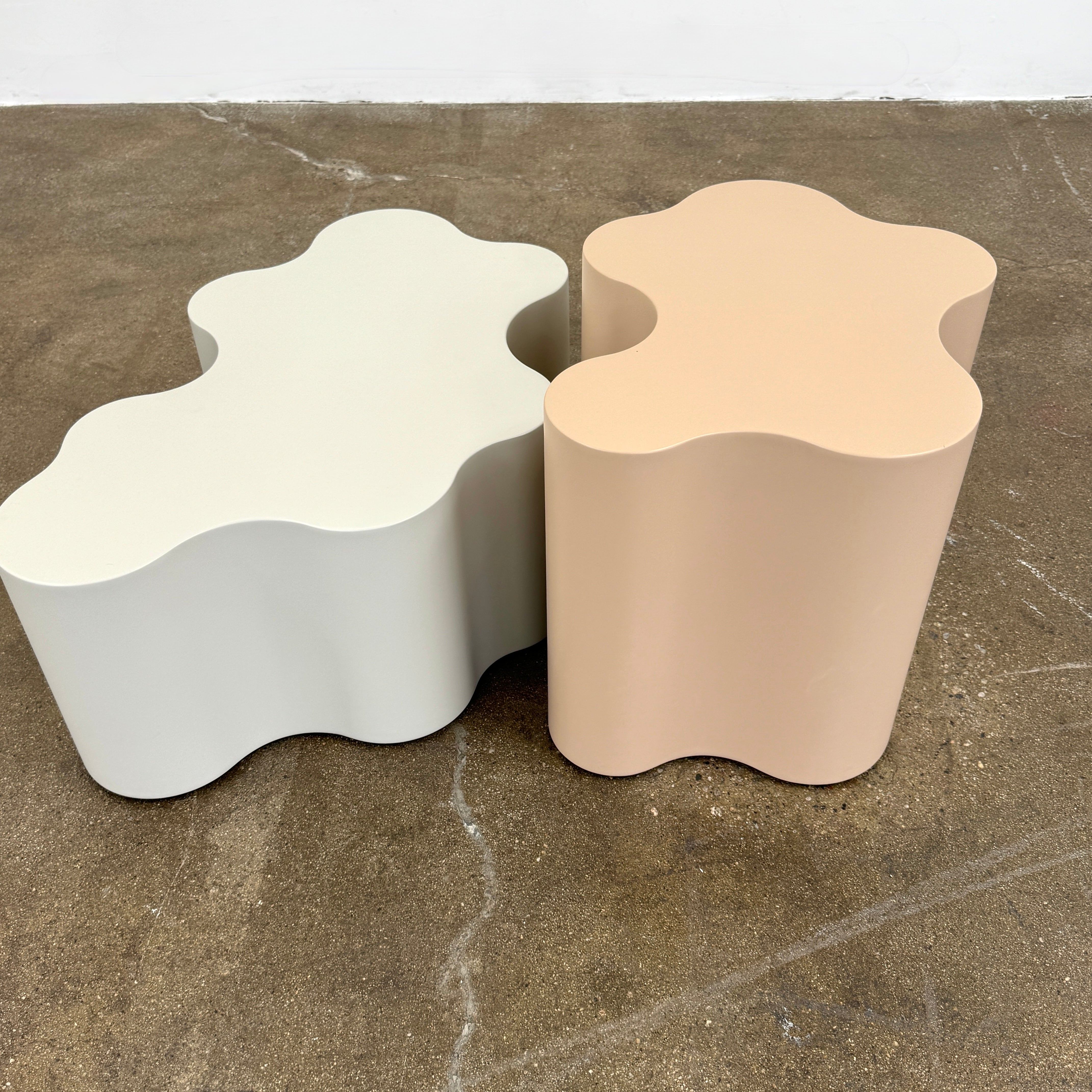 The Saba Italia Teatro Magico Table Set Grey + Nude by Saba Italia, with wavy edges and cloud shapes, sits on a polished concrete floor against a plain white wall.