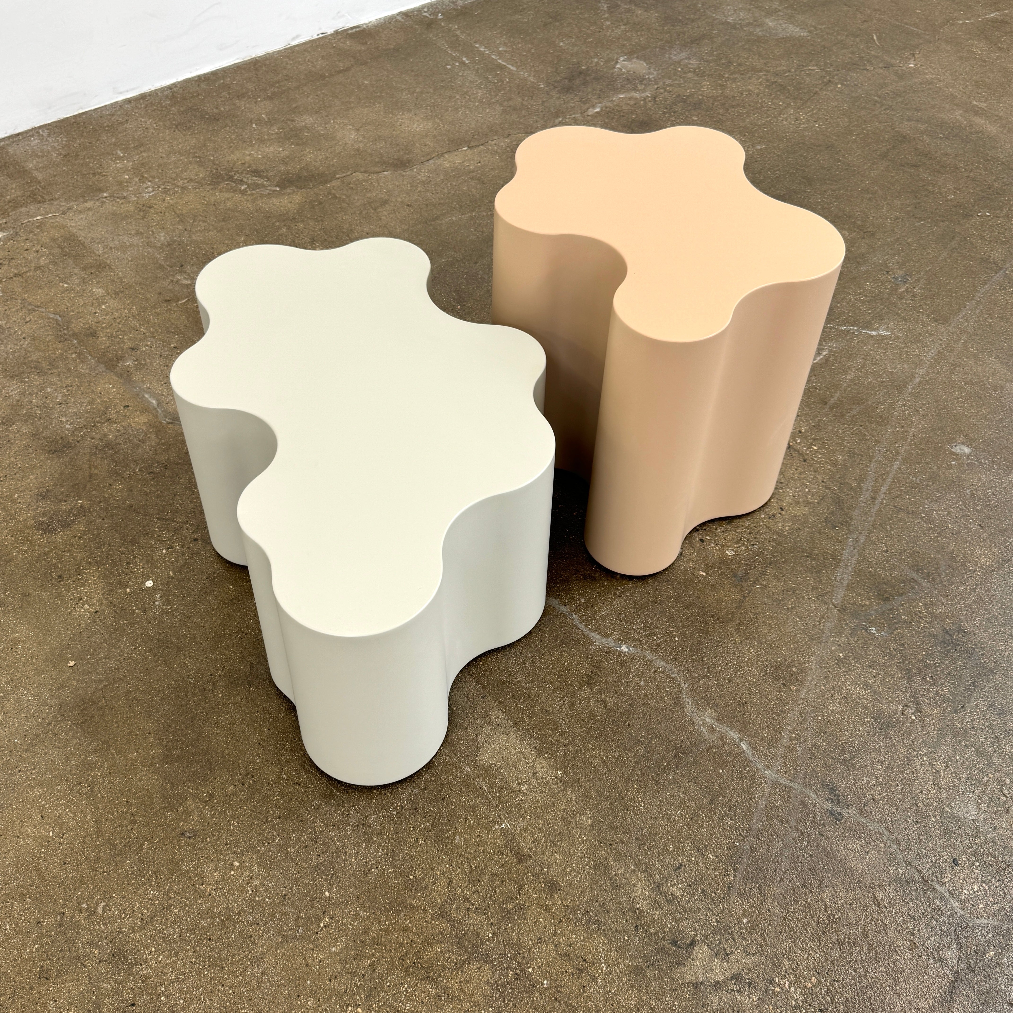 The Saba Italia Teatro Magico Table Set Grey + Nude by Saba Italia, with wavy edges and cloud shapes, sits on a polished concrete floor against a plain white wall.