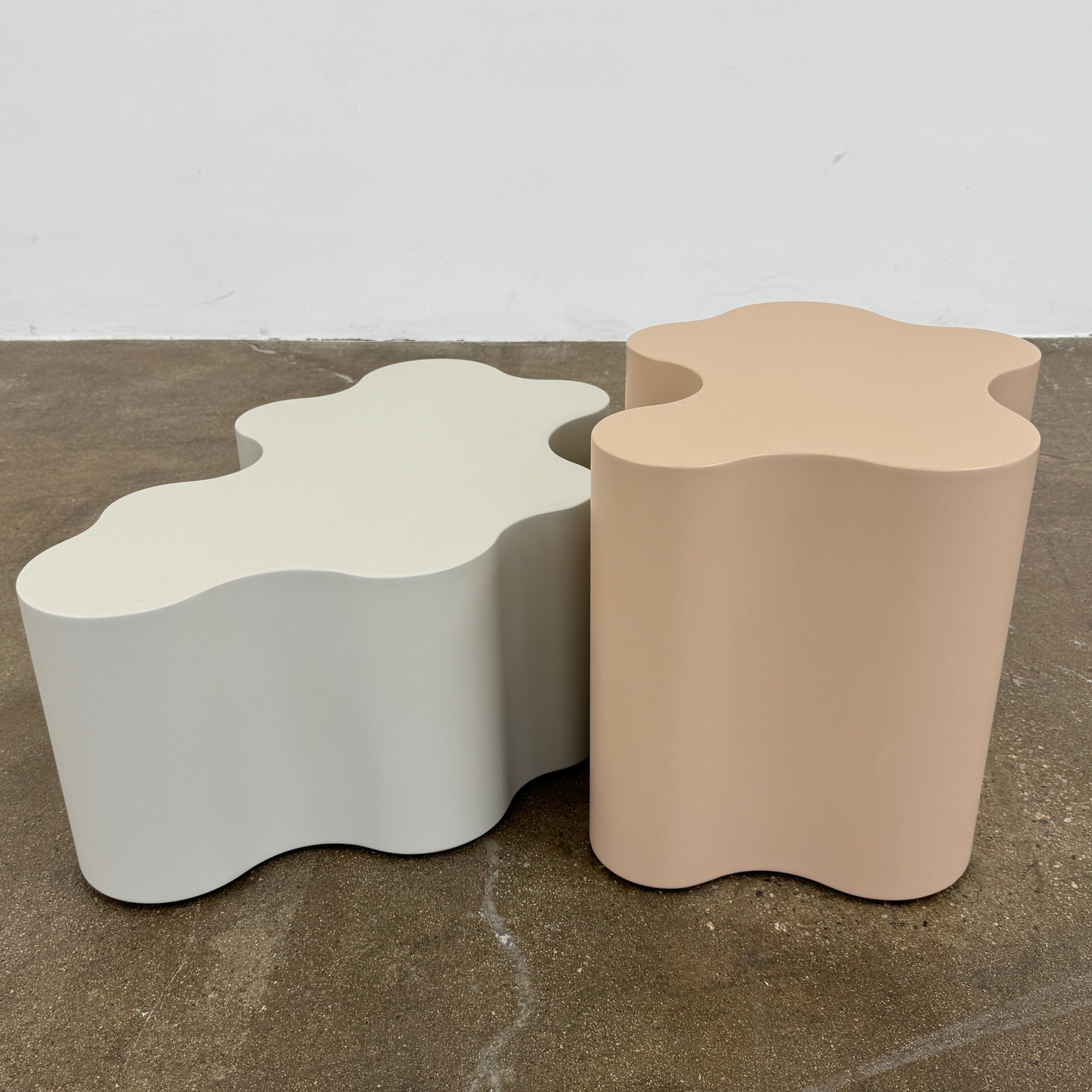 The Saba Italia Teatro Magico Table Set Grey + Nude by Saba Italia, with wavy edges and cloud shapes, sits on a polished concrete floor against a plain white wall.