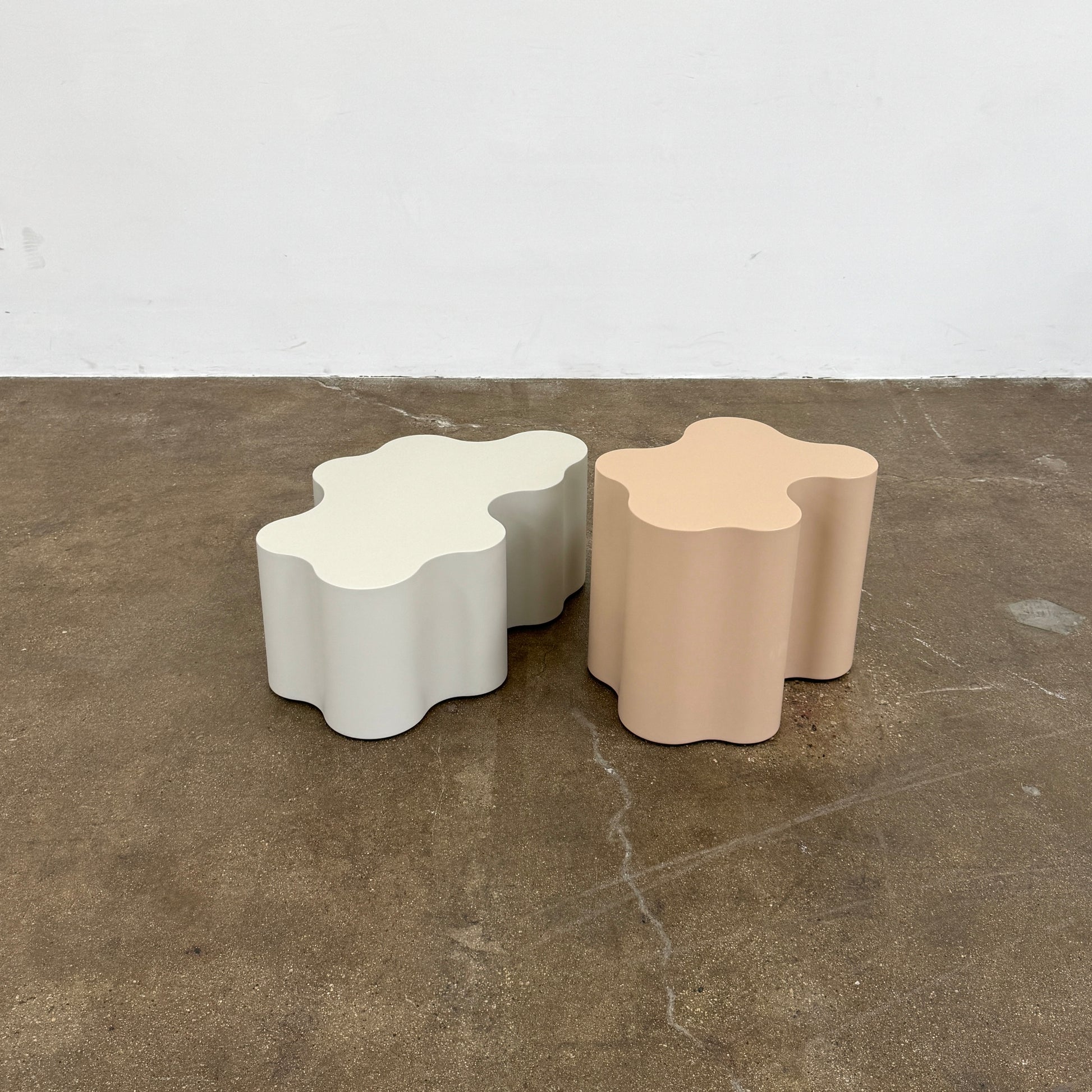 The Saba Italia Teatro Magico Table Set Grey + Nude by Saba Italia, with wavy edges and cloud shapes, sits on a polished concrete floor against a plain white wall.