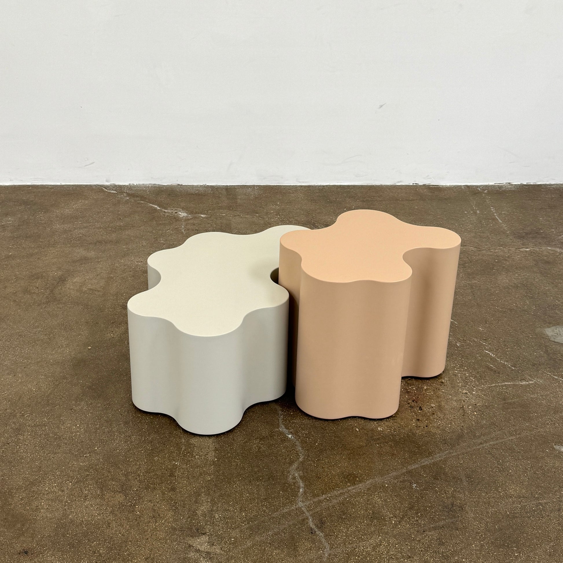 The Saba Italia Teatro Magico Table Set Grey + Nude by Saba Italia, with wavy edges and cloud shapes, sits on a polished concrete floor against a plain white wall.