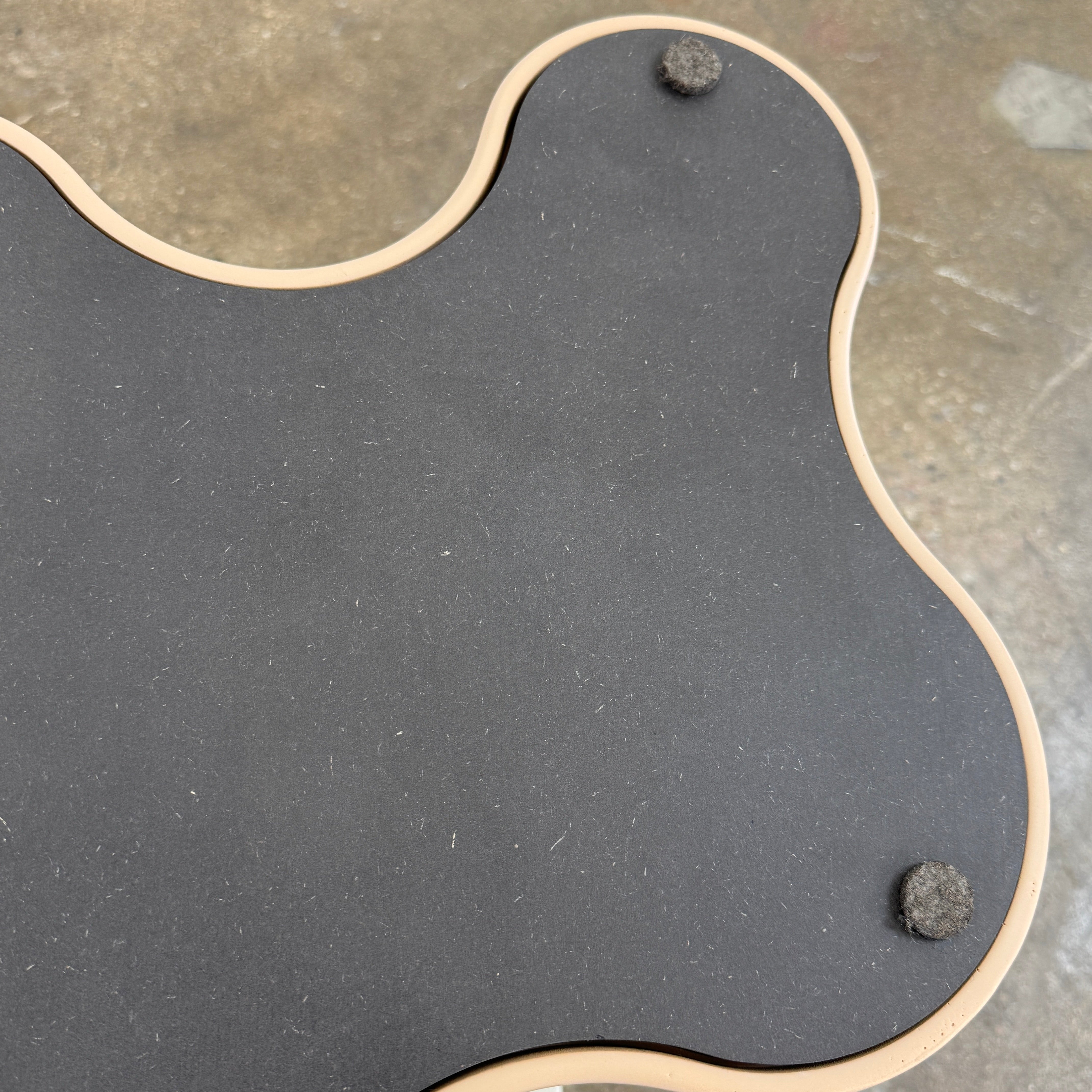 The Saba Italia Teatro Magico Table Set Grey + Nude by Saba Italia, with wavy edges and cloud shapes, sits on a polished concrete floor against a plain white wall.