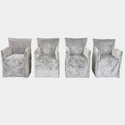 Four Gervasoni Ghost 25 Dining Armchairs by Gervasoni, featuring straight backs and skirted slipcovers in silver velvet, are arranged side by side against a white background for an elegant look.