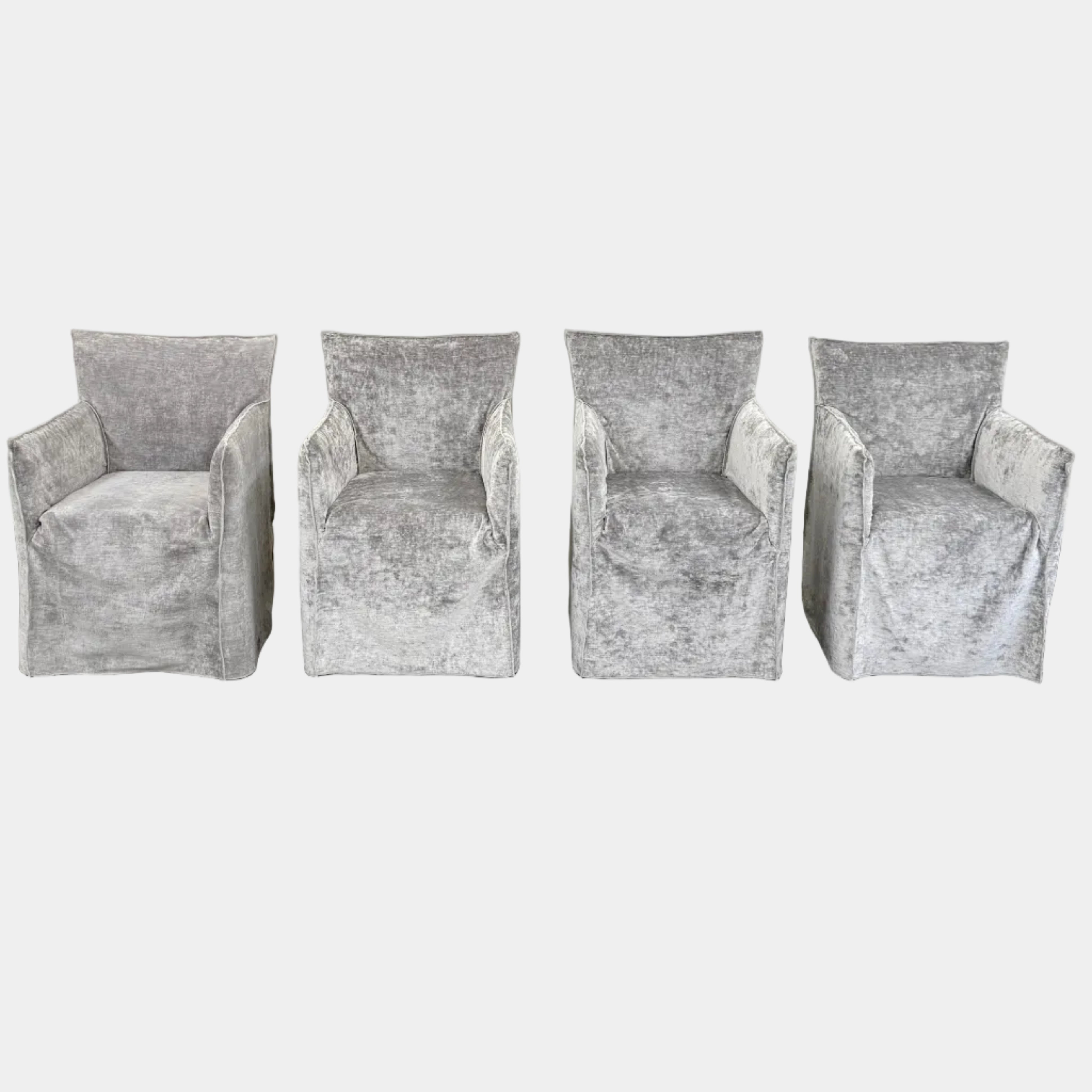 Four Gervasoni Ghost 25 Dining Armchairs by Gervasoni, featuring straight backs and skirted slipcovers in silver velvet, are arranged side by side against a white background for an elegant look.