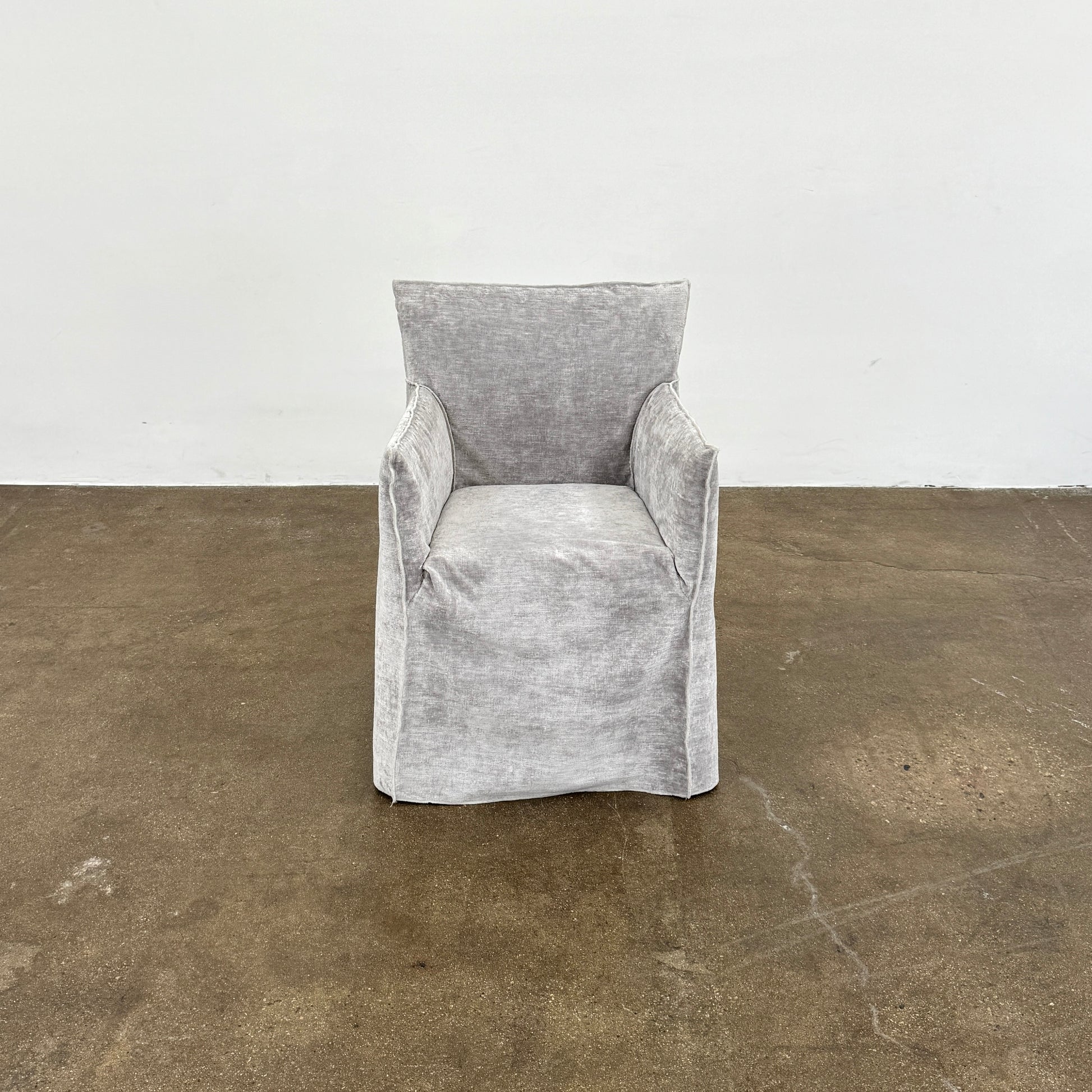 Four Gervasoni Ghost 25 Dining Armchairs by Gervasoni, featuring straight backs and skirted slipcovers in silver velvet, are arranged side by side against a white background for an elegant look.