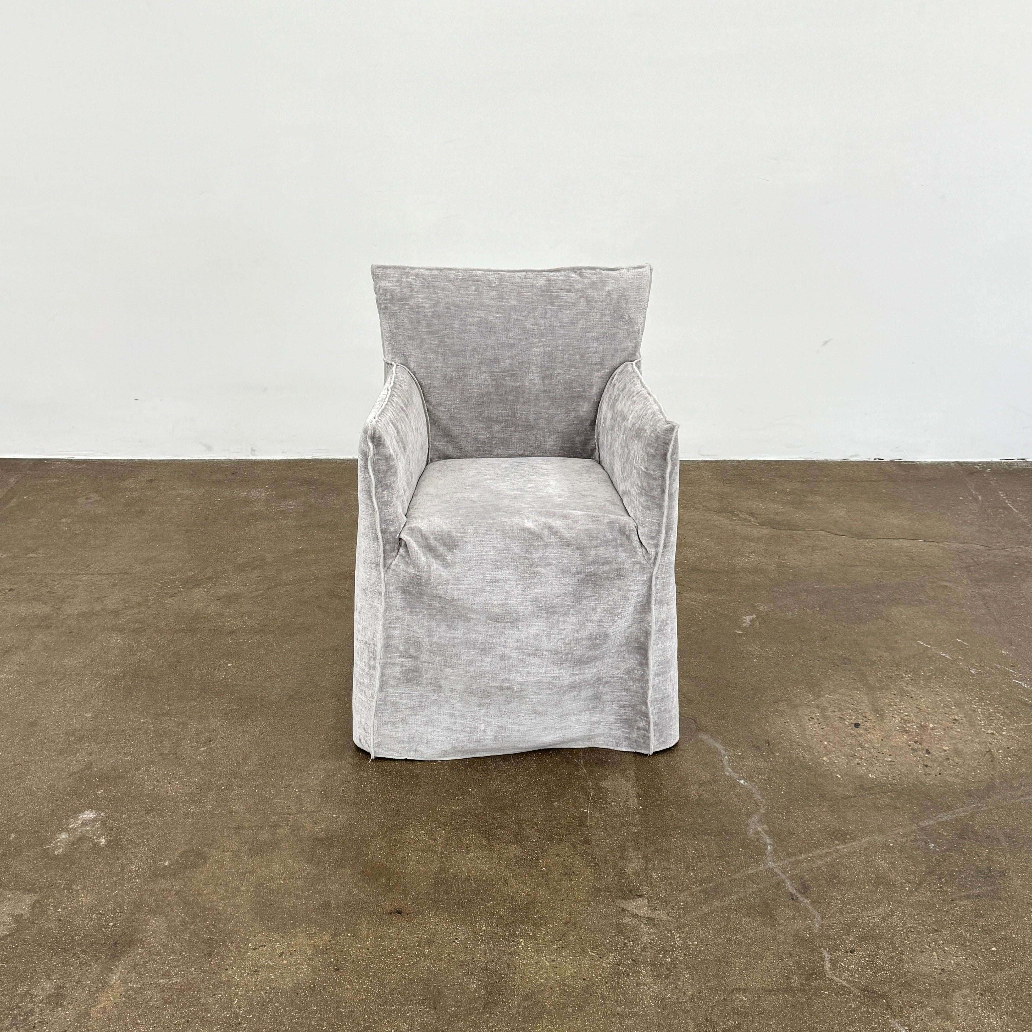 Four Gervasoni Ghost 25 Dining Armchairs by Gervasoni, featuring straight backs and skirted slipcovers in silver velvet, are arranged side by side against a white background for an elegant look.