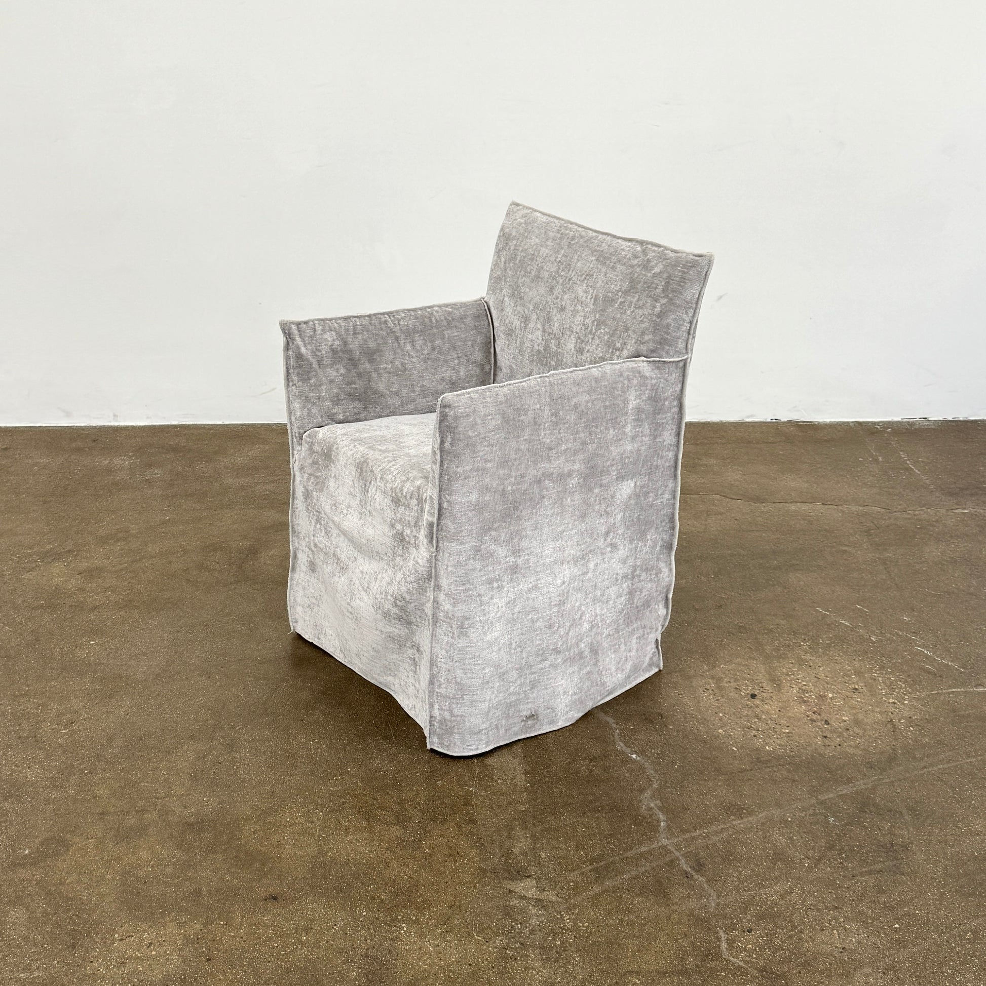 Four Gervasoni Ghost 25 Dining Armchairs by Gervasoni, featuring straight backs and skirted slipcovers in silver velvet, are arranged side by side against a white background for an elegant look.