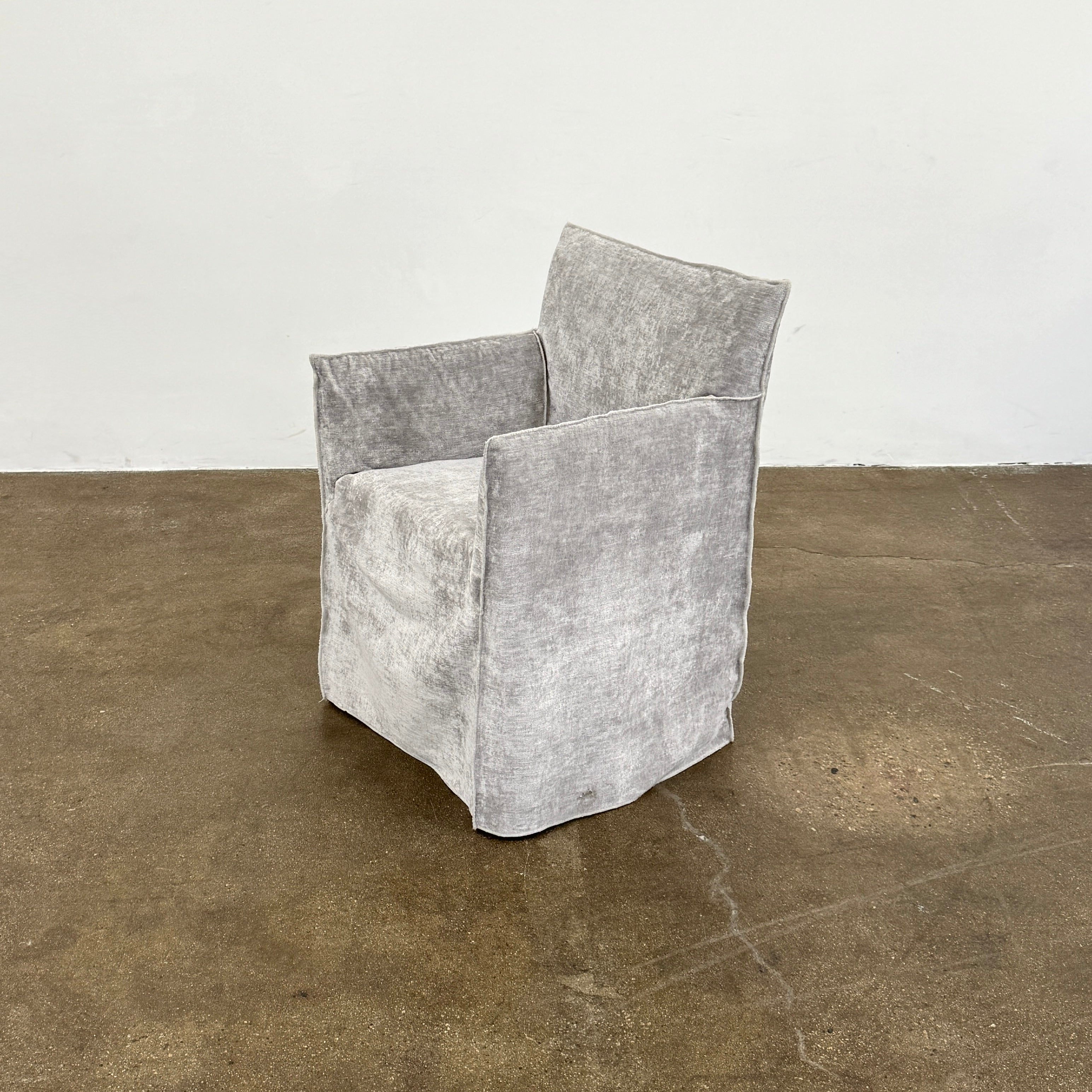 Four Gervasoni Ghost 25 Dining Armchairs by Gervasoni, featuring straight backs and skirted slipcovers in silver velvet, are arranged side by side against a white background for an elegant look.