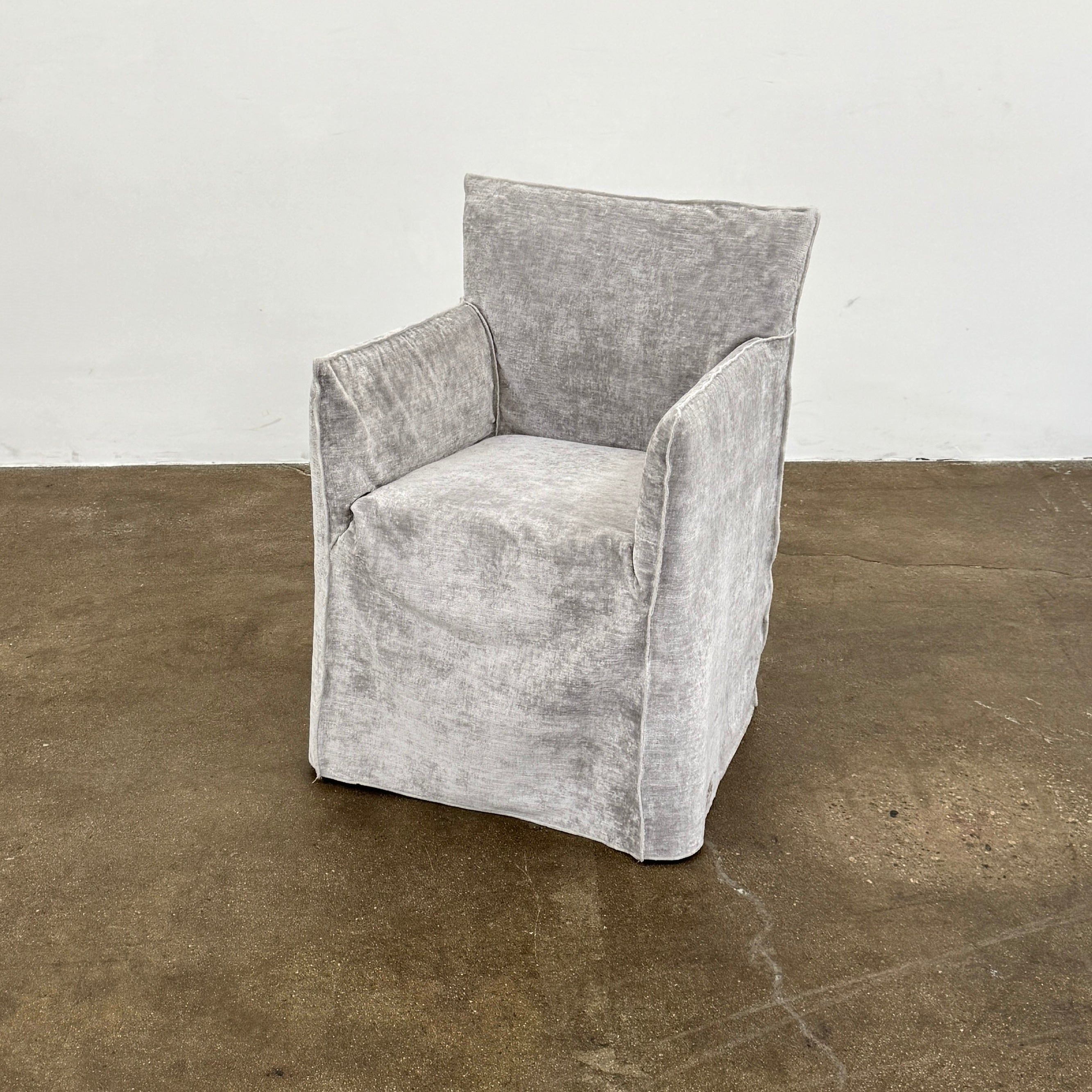 Four Gervasoni Ghost 25 Dining Armchairs by Gervasoni, featuring straight backs and skirted slipcovers in silver velvet, are arranged side by side against a white background for an elegant look.