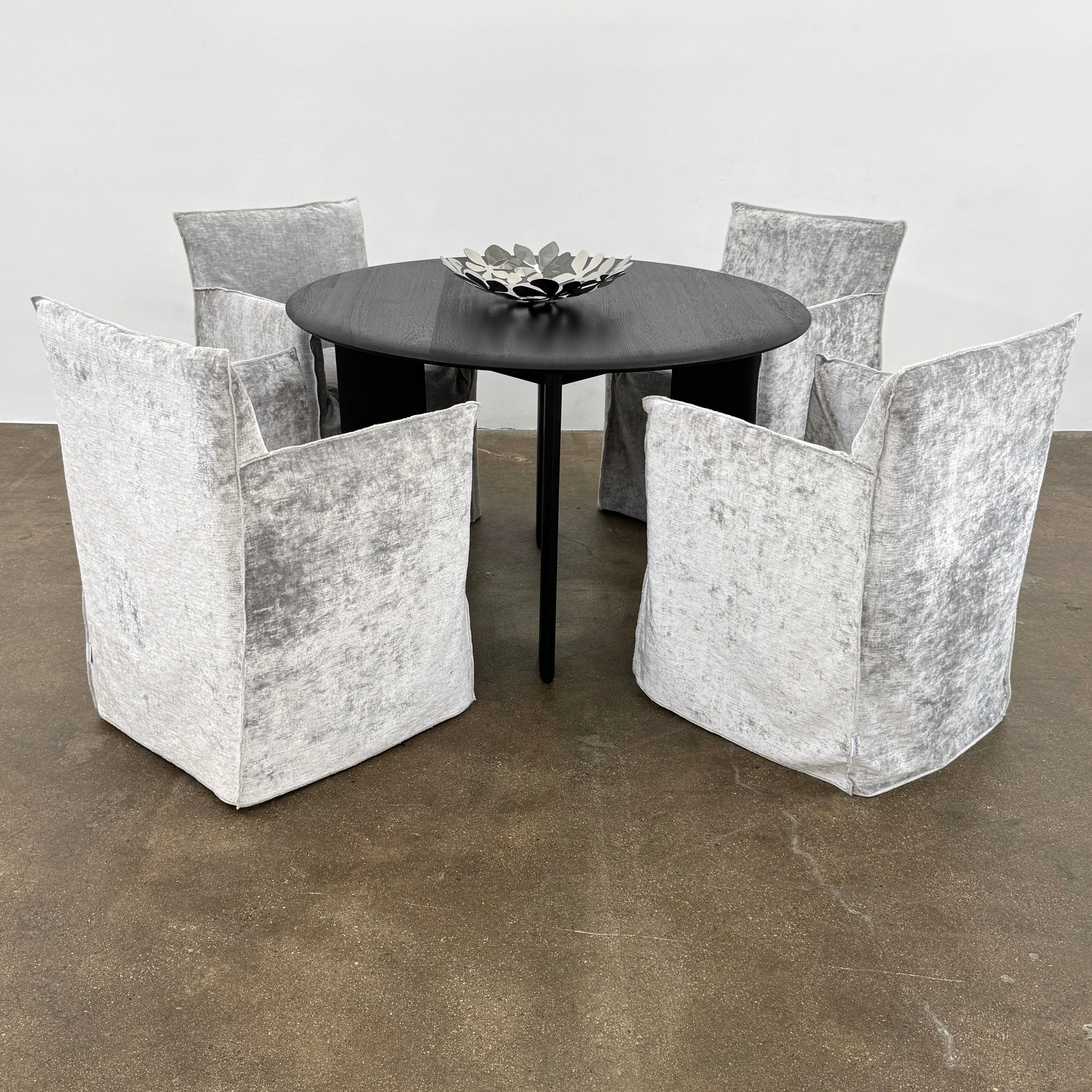 Four Gervasoni Ghost 25 Dining Armchairs by Gervasoni, featuring straight backs and skirted slipcovers in silver velvet, are arranged side by side against a white background for an elegant look.