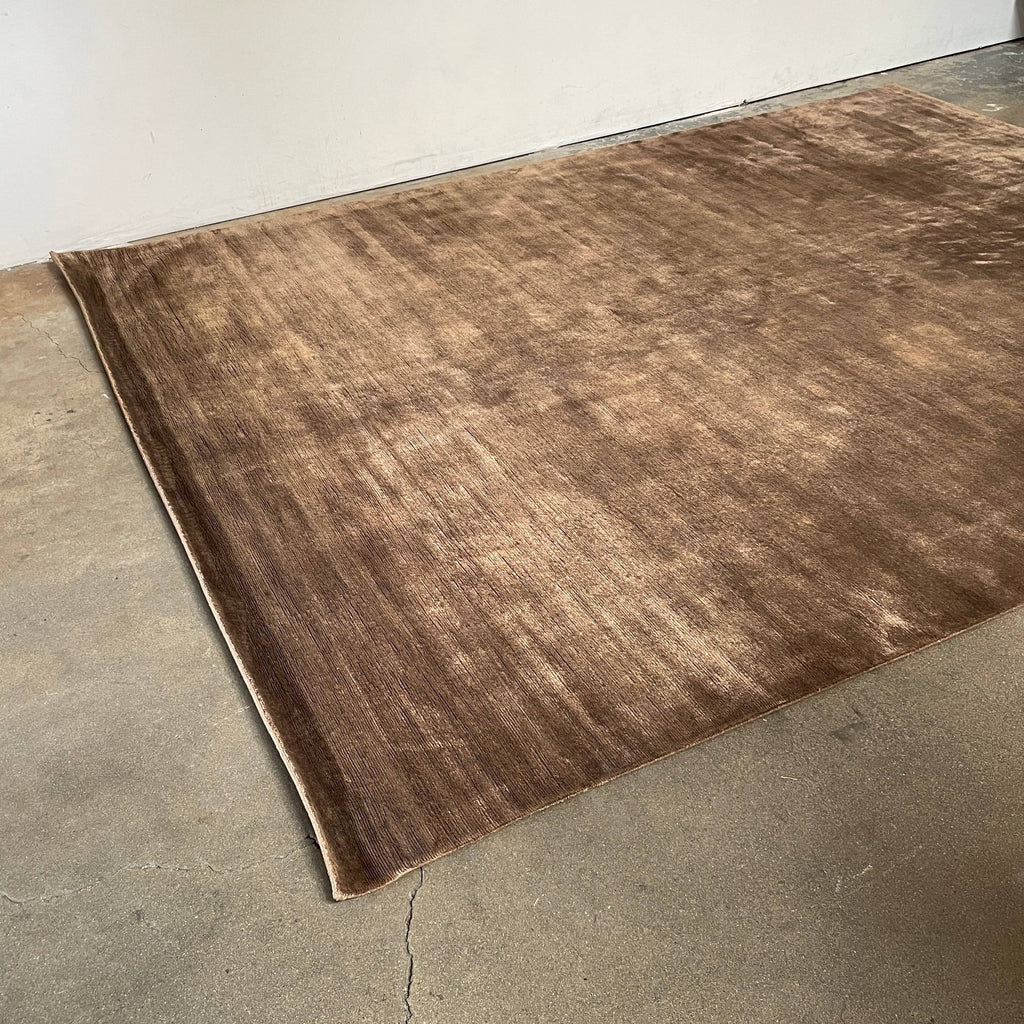 A Delinear Bamboo 8' X 10' rug laid out on a flat surface with lighting creating shadows and highlights on its surface.