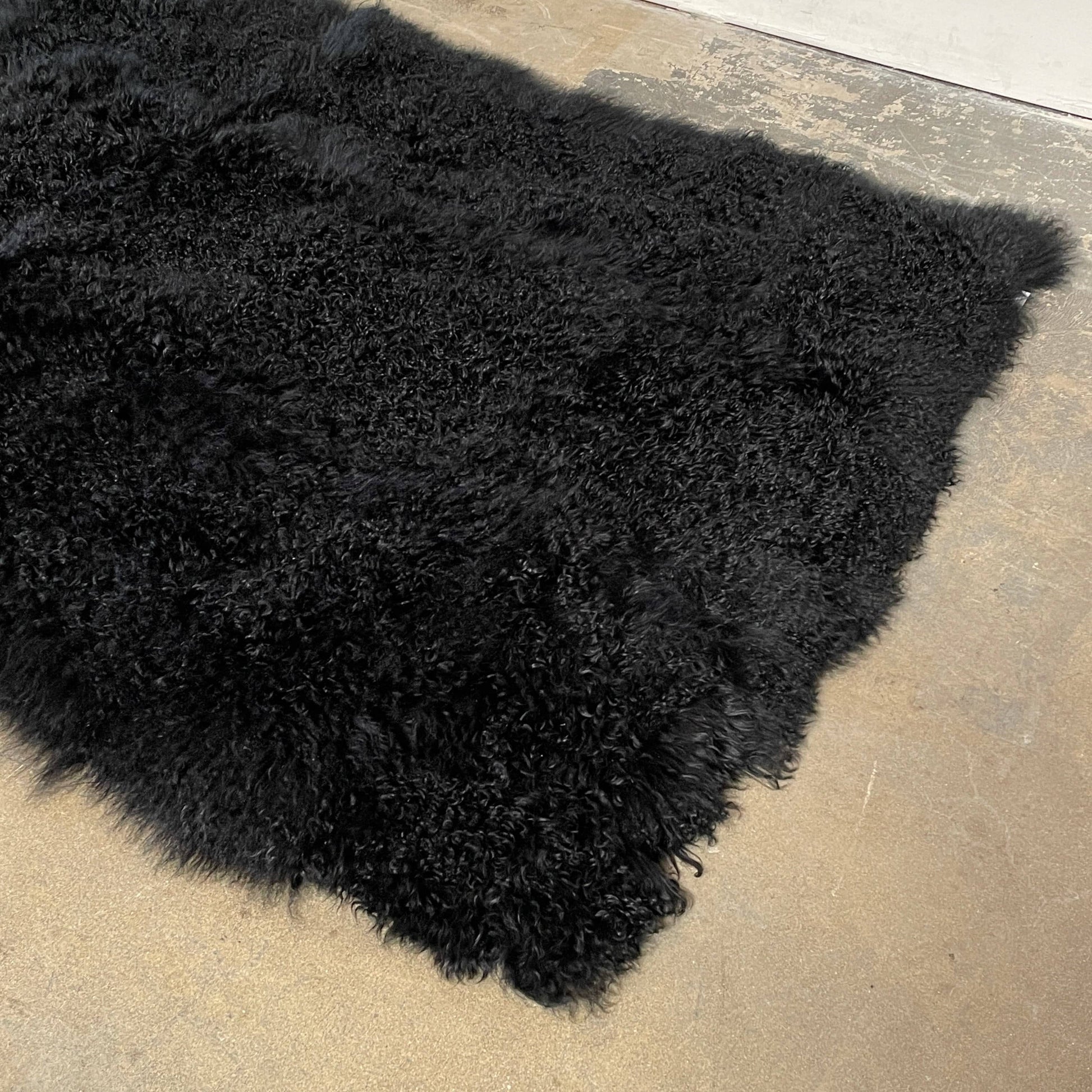 Black Icelandic Sheepskin 5' x 7' rug with a shaggy appearance against a white background.