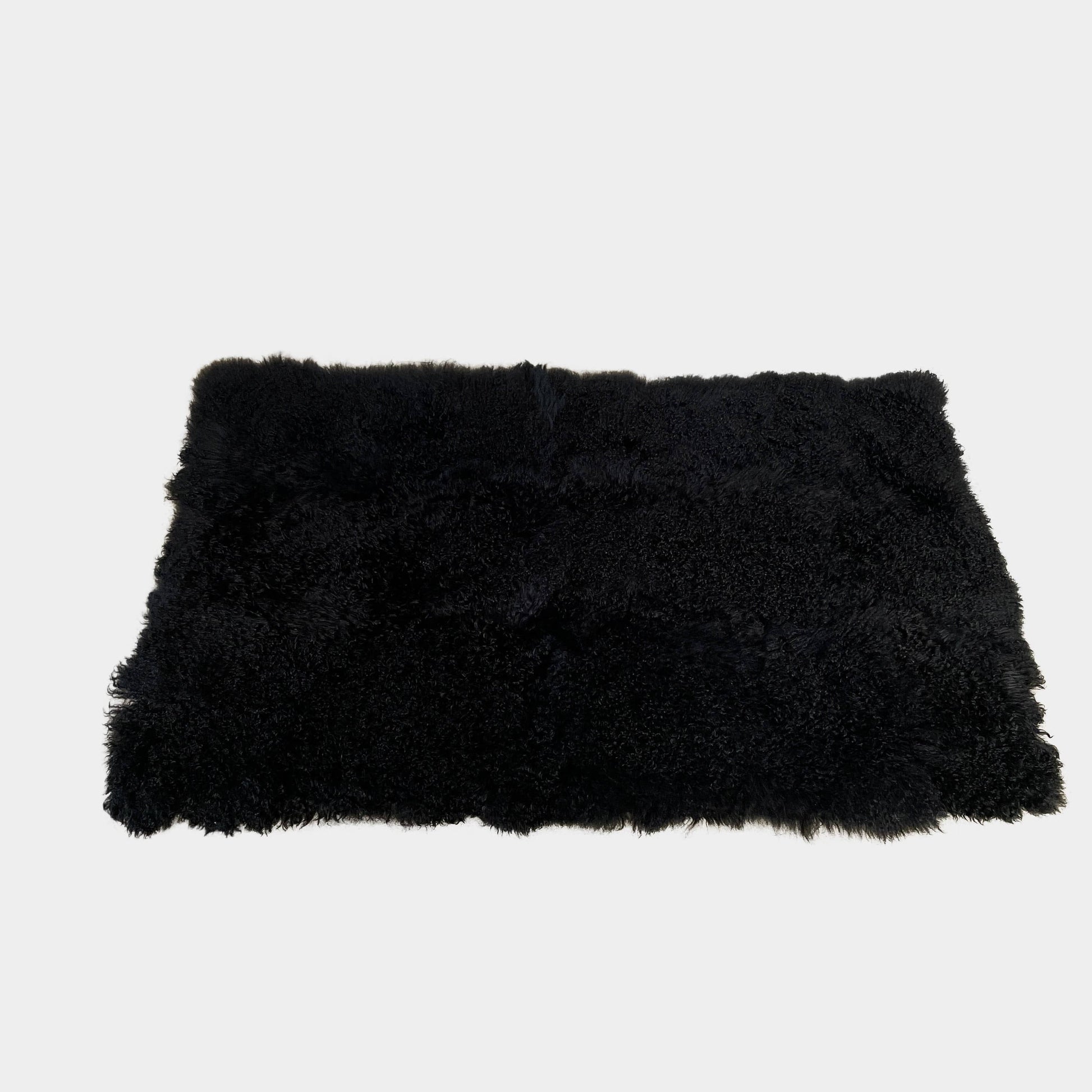 Black Icelandic Sheepskin 5' x 7' rug with a shaggy appearance against a white background.