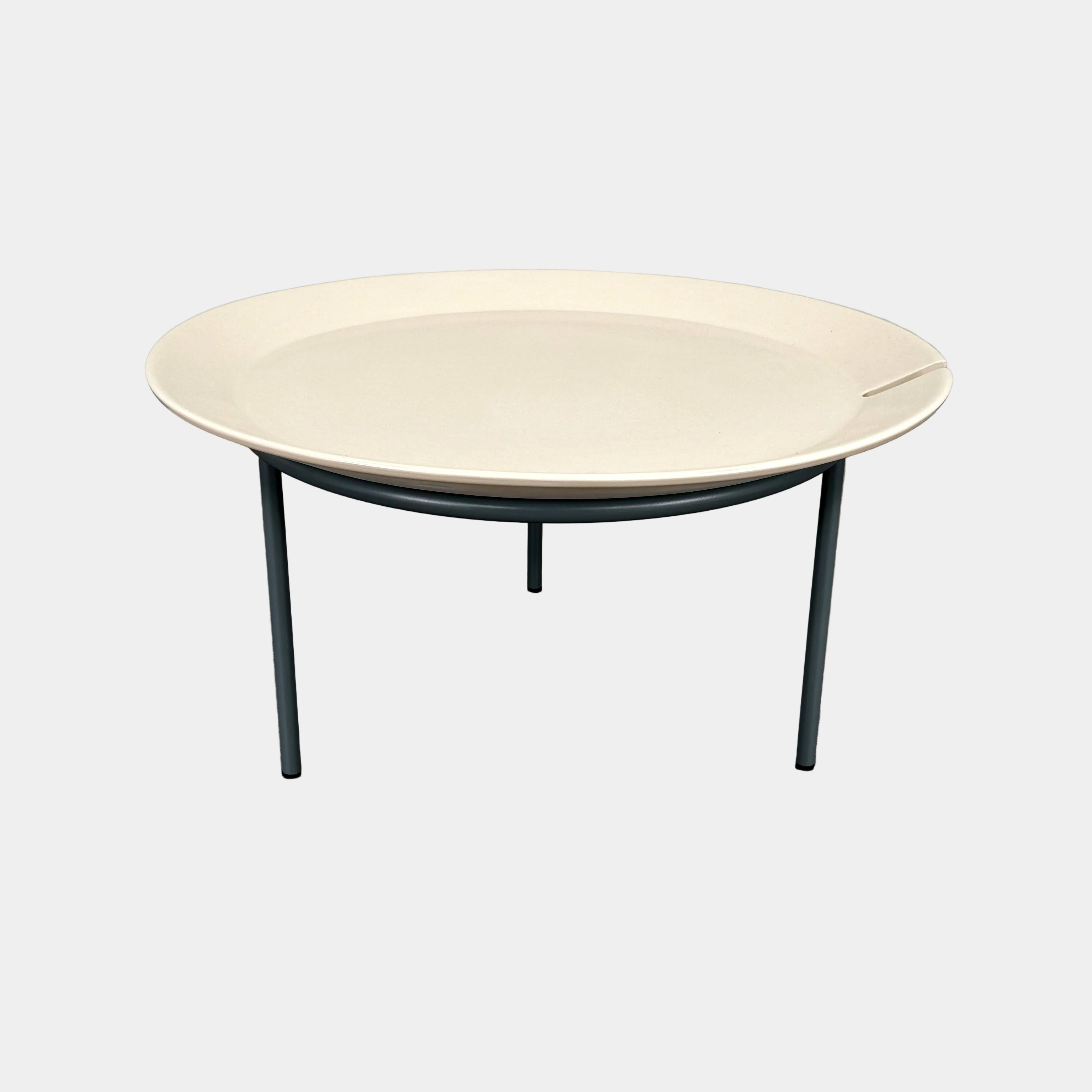 The Gervasoni Brise 54 Outdoor Coffee Table by Gervasoni features a round beige tray top and three black metal legs, shown against a light grey background—perfect for adding modern style to outdoor spaces.