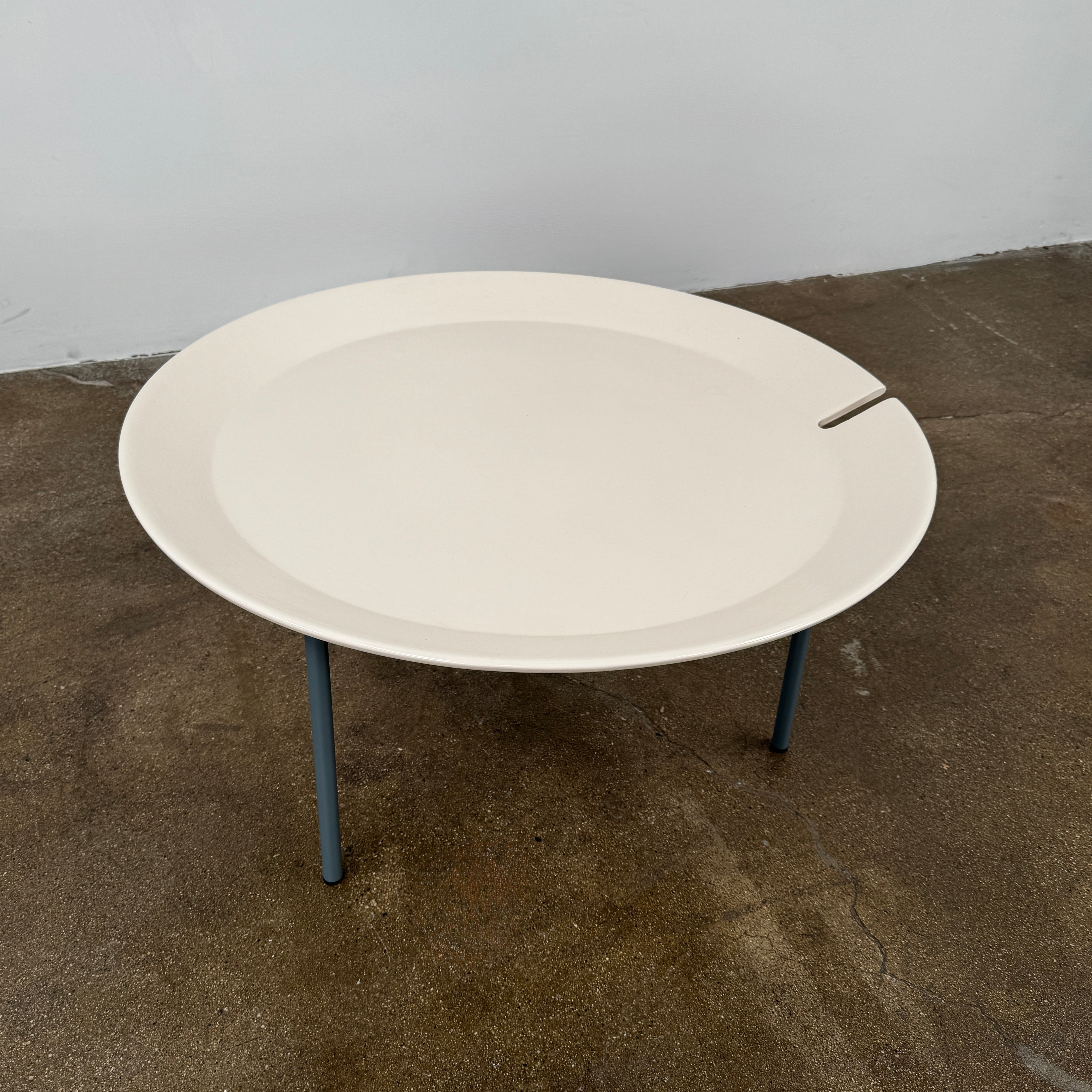 The Gervasoni Brise 54 Outdoor Coffee Table by Gervasoni features a round beige tray top and three black metal legs, shown against a light grey background—perfect for adding modern style to outdoor spaces.