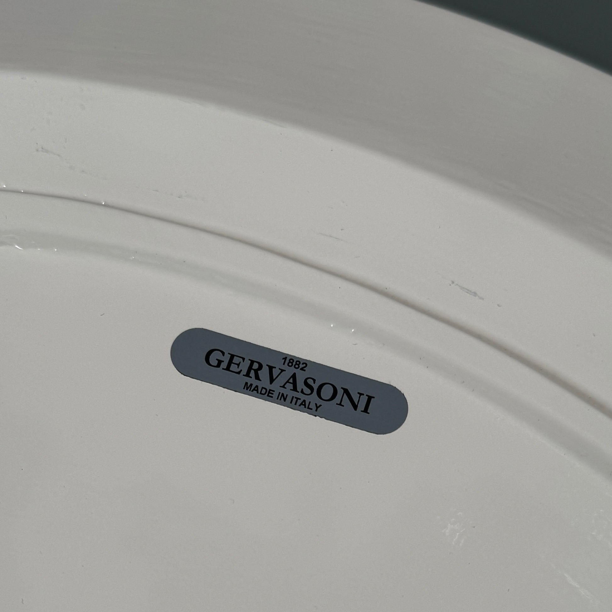 The Gervasoni Brise 54 Outdoor Coffee Table by Gervasoni features a round beige tray top and three black metal legs, shown against a light grey background—perfect for adding modern style to outdoor spaces.