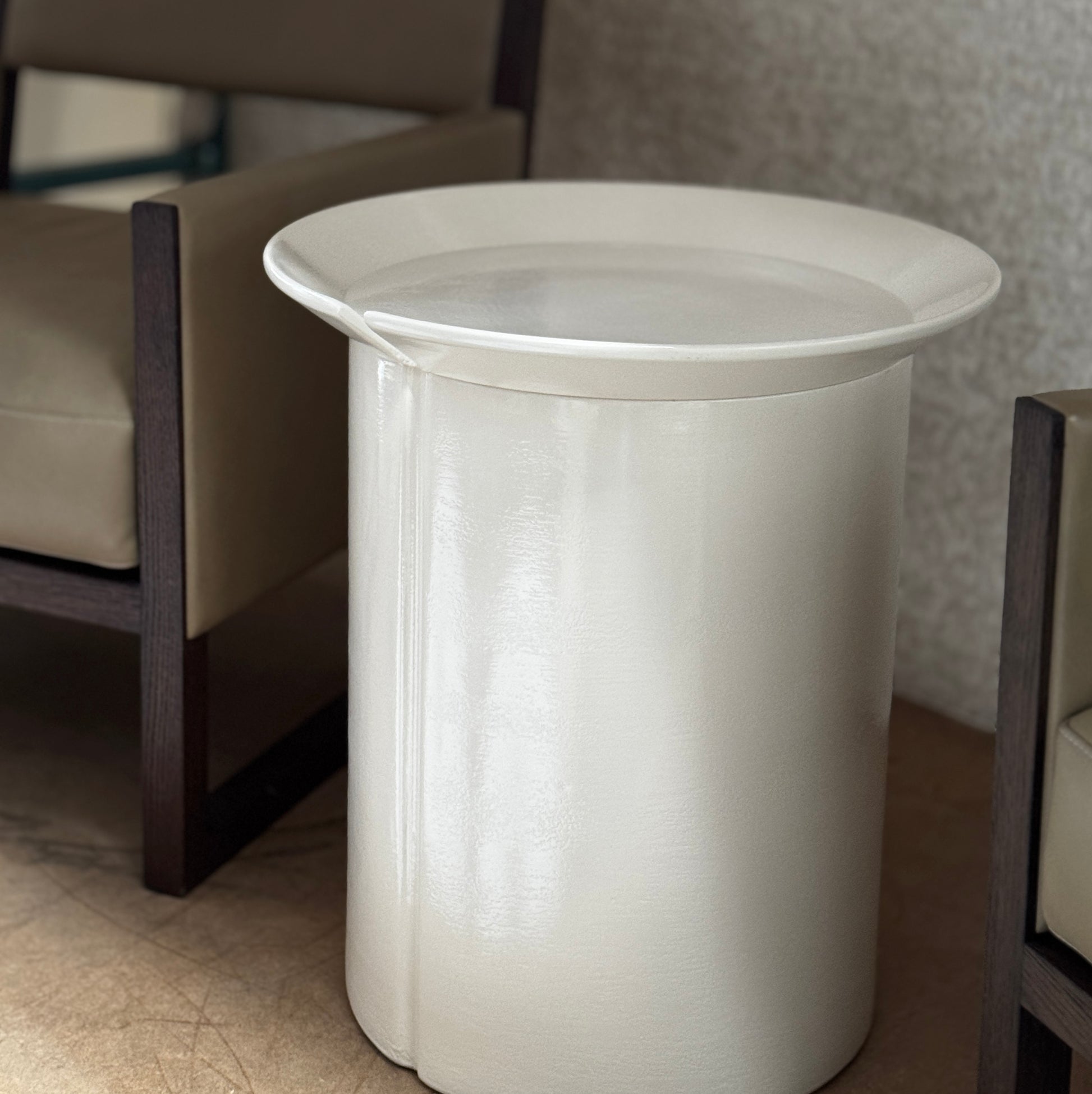 The Gervasoni Brise 43 Side Table by Gervasoni features a beige, cylindrical shape with a wide, subtly flared rim and a vertical seam, evoking Art Nouveau influences, shown against a plain white background.