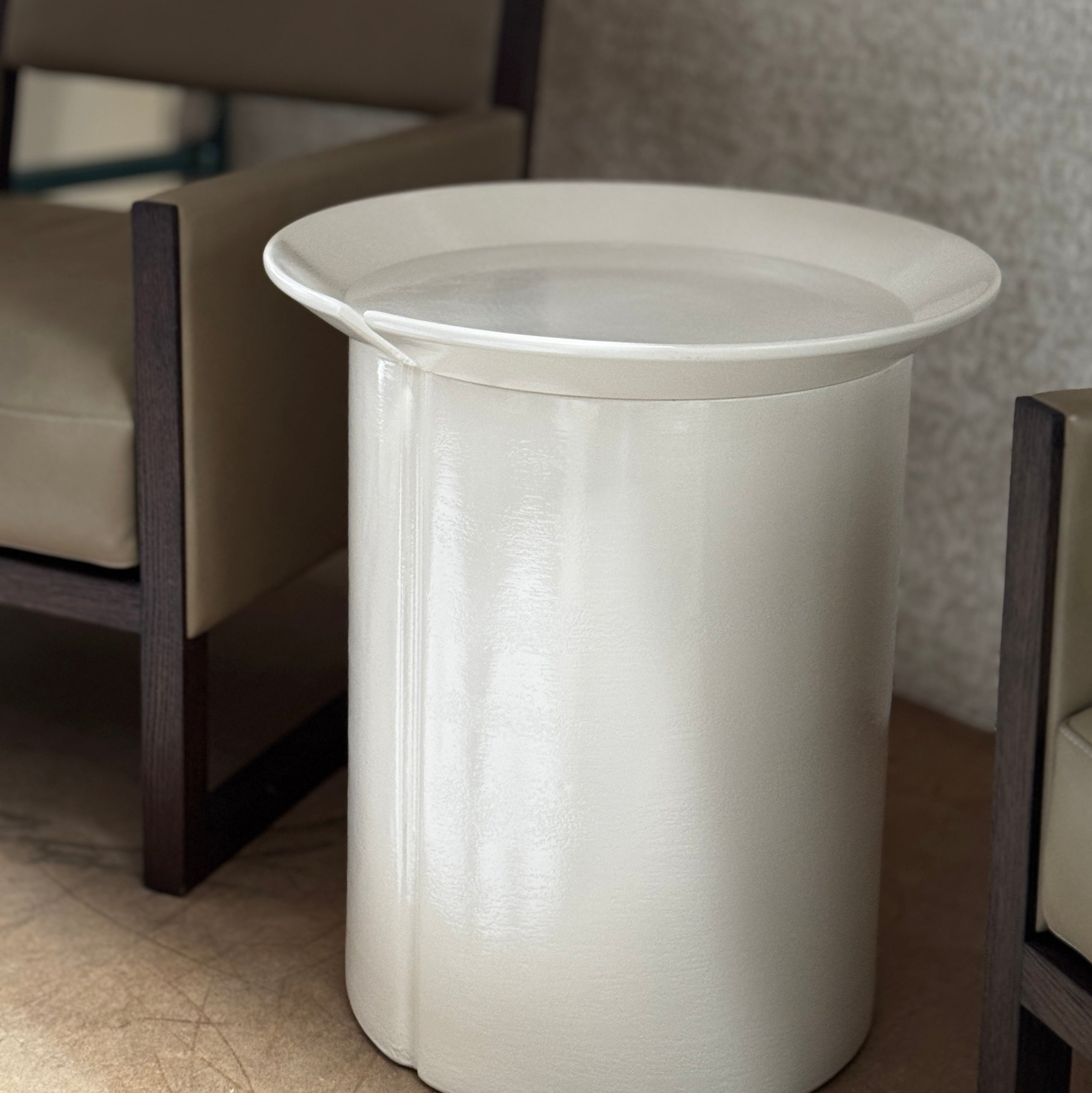 The Gervasoni Brise 43 Side Table by Gervasoni features a beige, cylindrical shape with a wide, subtly flared rim and a vertical seam, evoking Art Nouveau influences, shown against a plain white background.