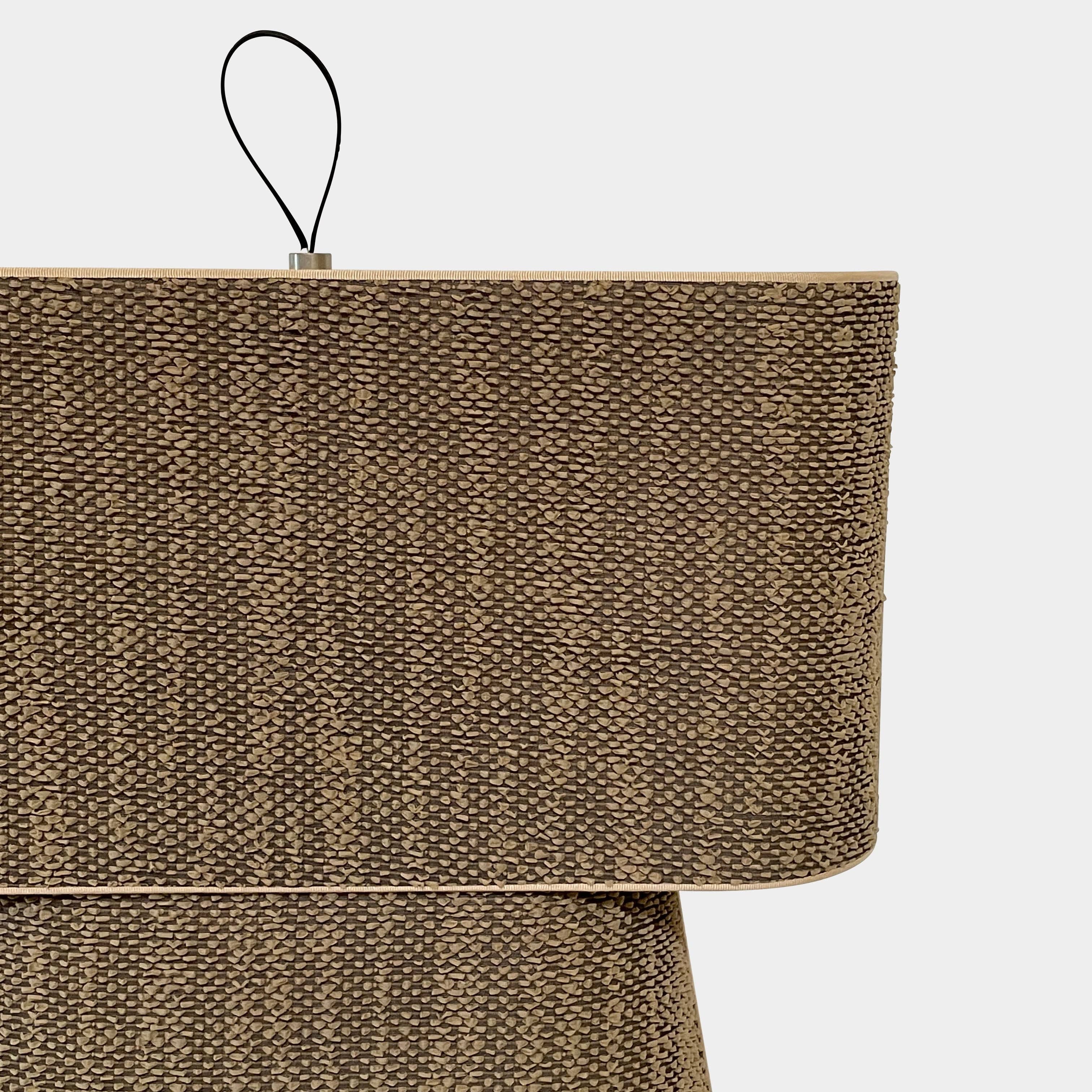 Two-tiered, textured fabric lampshade with a loop finial on a white background for the Luminara Dabliu Table Light by Luminara.