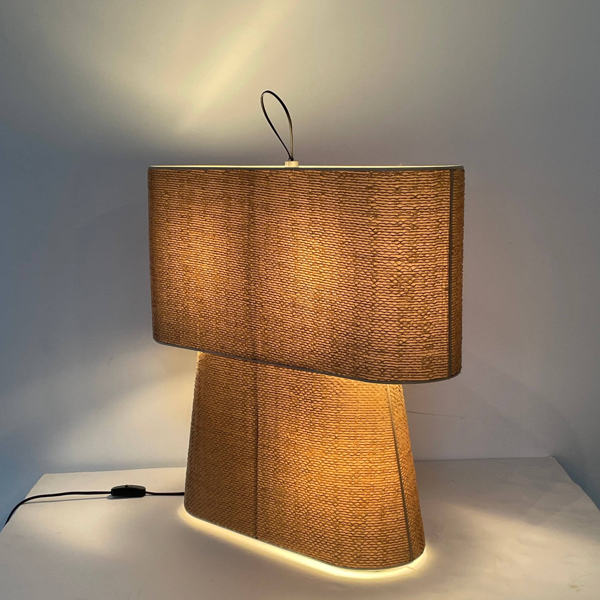 Two-tiered, textured fabric lampshade with a loop finial on a white background for the Luminara Dabliu Table Light by Luminara.