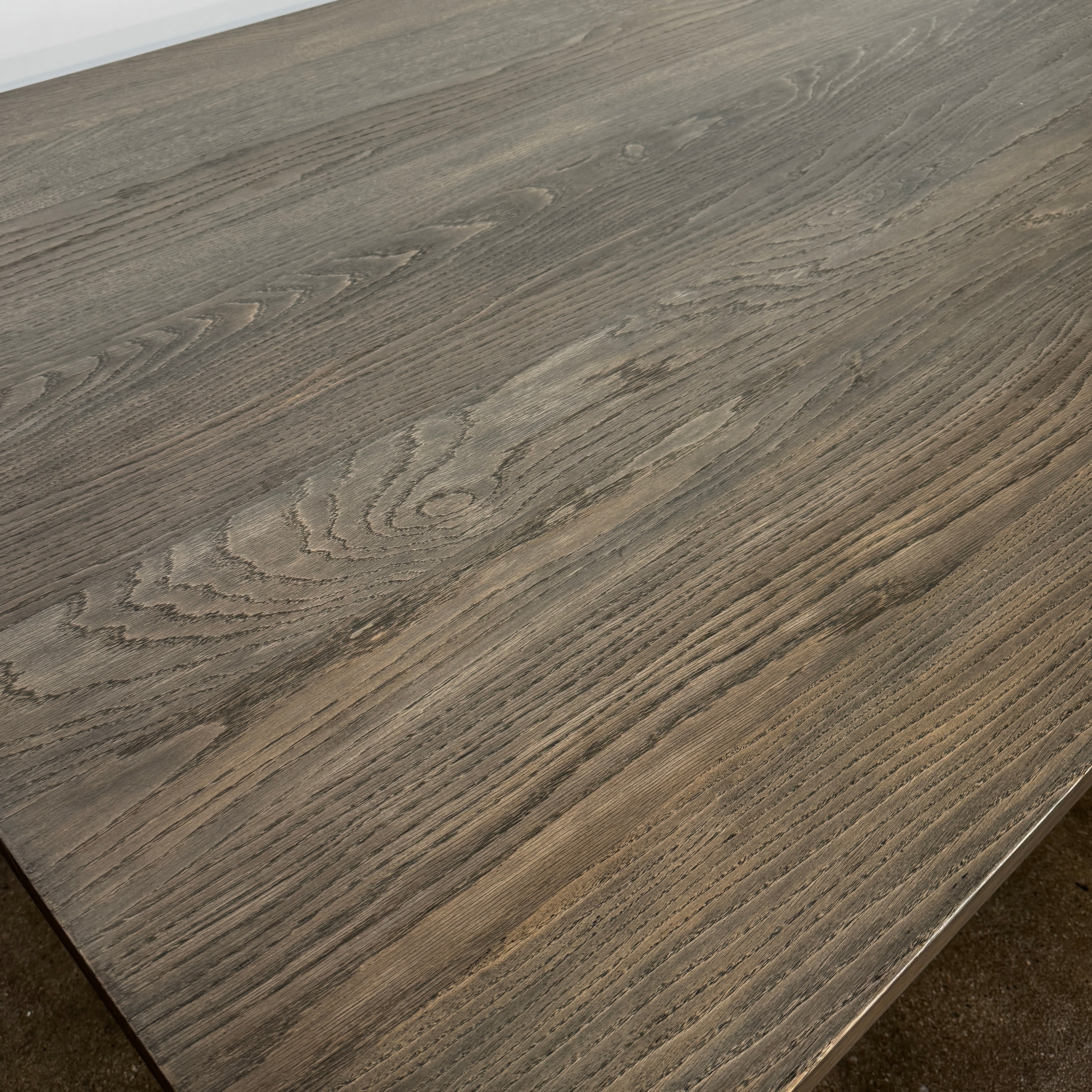 The BDDW Solid Oak dining table by BDDW features a simple, modern rectangular design and is set against a plain white wall on a polished concrete floor.