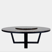 The Maxalto Xilos Dining Table with Rotating Tray by Maxalto features a round, dark finish and a black geometric base, shown here against a plain light background.