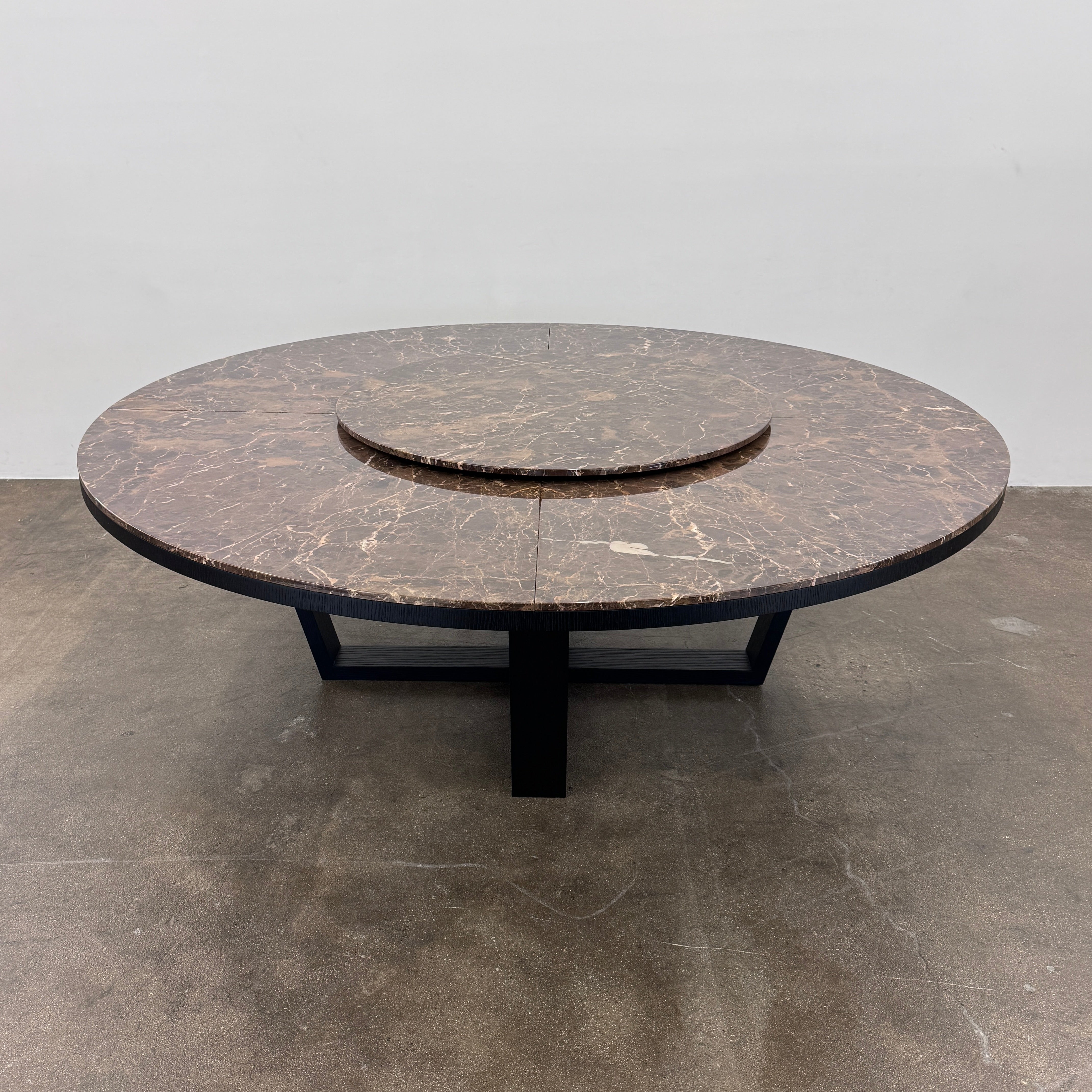 The Maxalto Xilos Dining Table with Rotating Tray by Maxalto features a round, dark finish and a black geometric base, shown here against a plain light background.