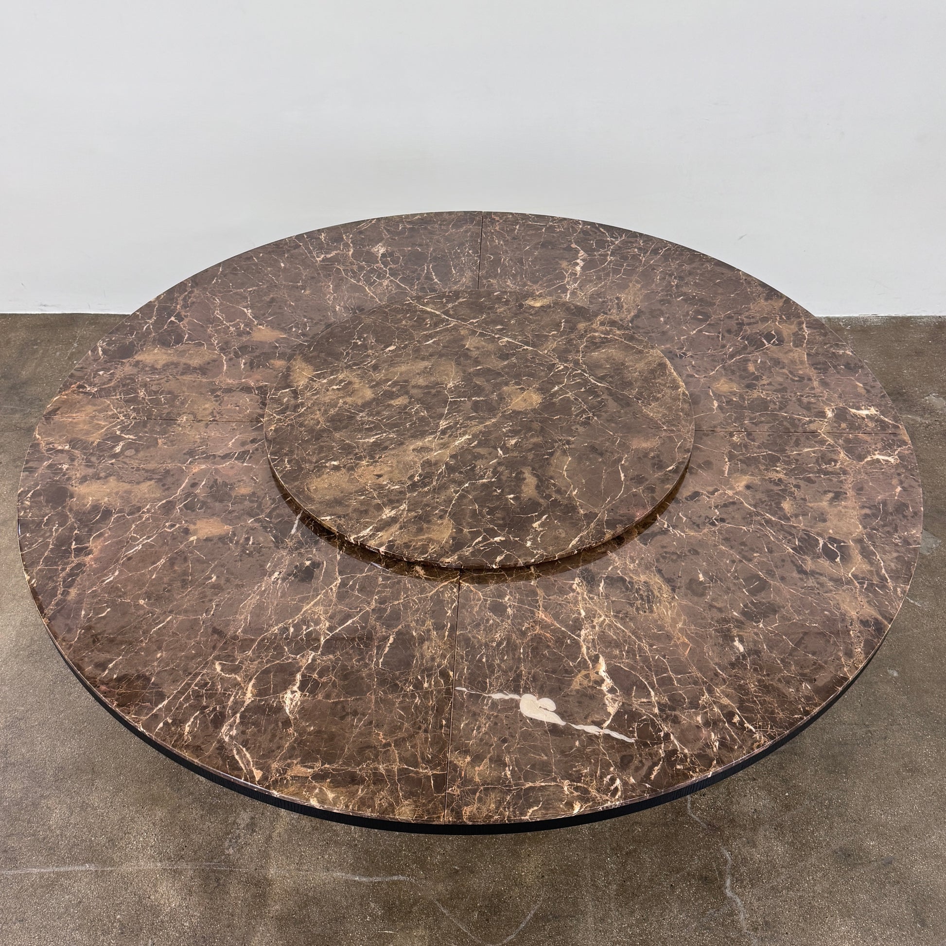 The Maxalto Xilos Dining Table with Rotating Tray by Maxalto features a round, dark finish and a black geometric base, shown here against a plain light background.