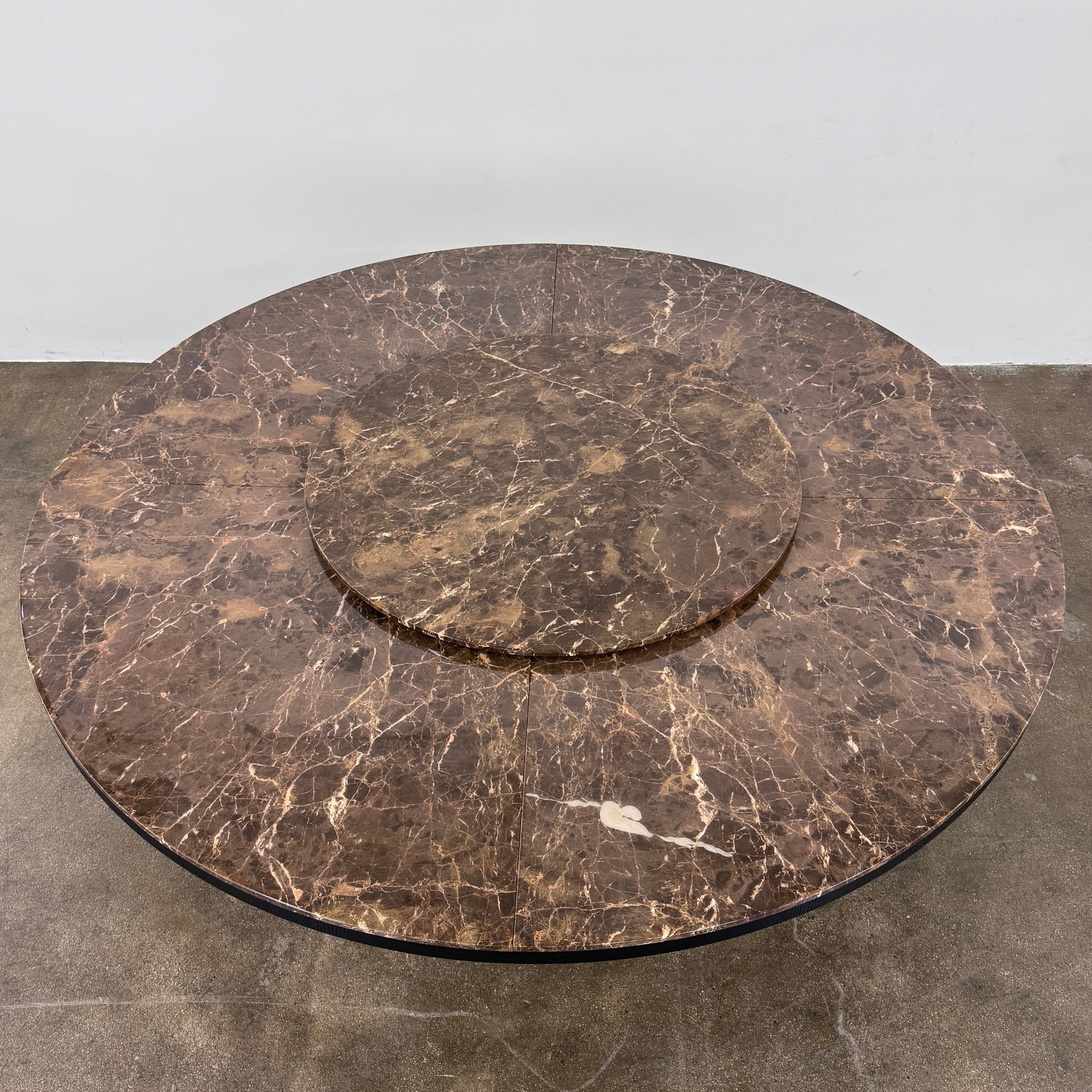 The Maxalto Xilos Dining Table with Rotating Tray by Maxalto features a round, dark finish and a black geometric base, shown here against a plain light background.