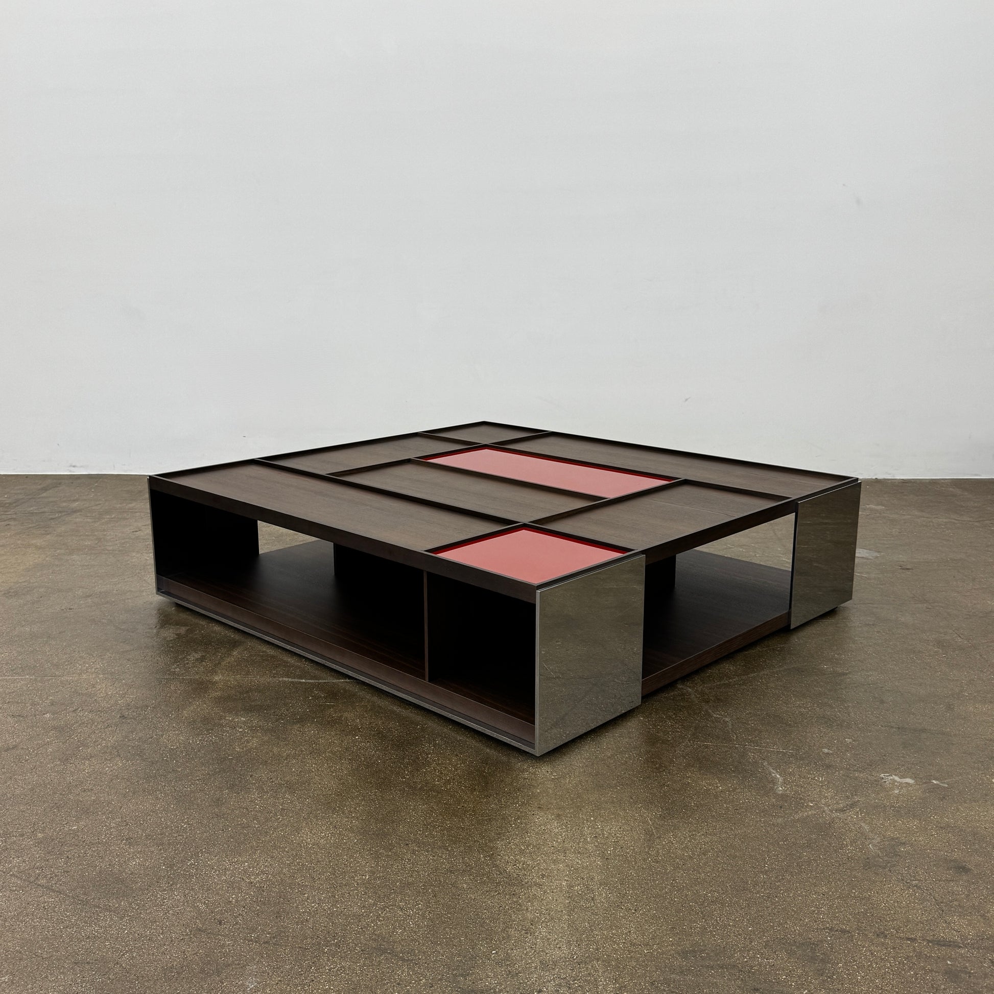 A modern square coffee table by B&B Italia, the Surface Coffee Table features wood, concrete-like panels, and two red rectangular accents—ideal for admirers of geometric designer furniture.