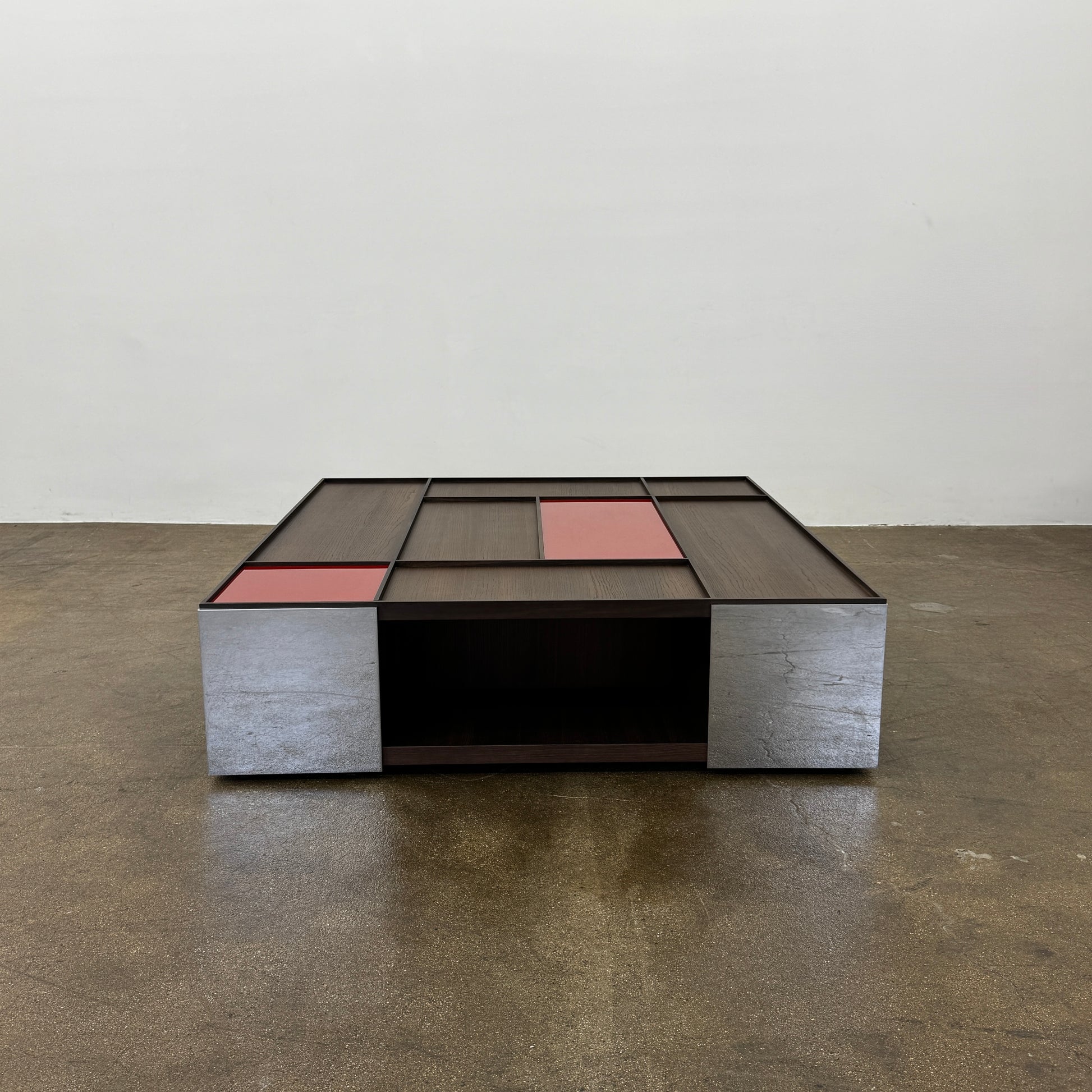 A modern square coffee table by B&B Italia, the Surface Coffee Table features wood, concrete-like panels, and two red rectangular accents—ideal for admirers of geometric designer furniture.