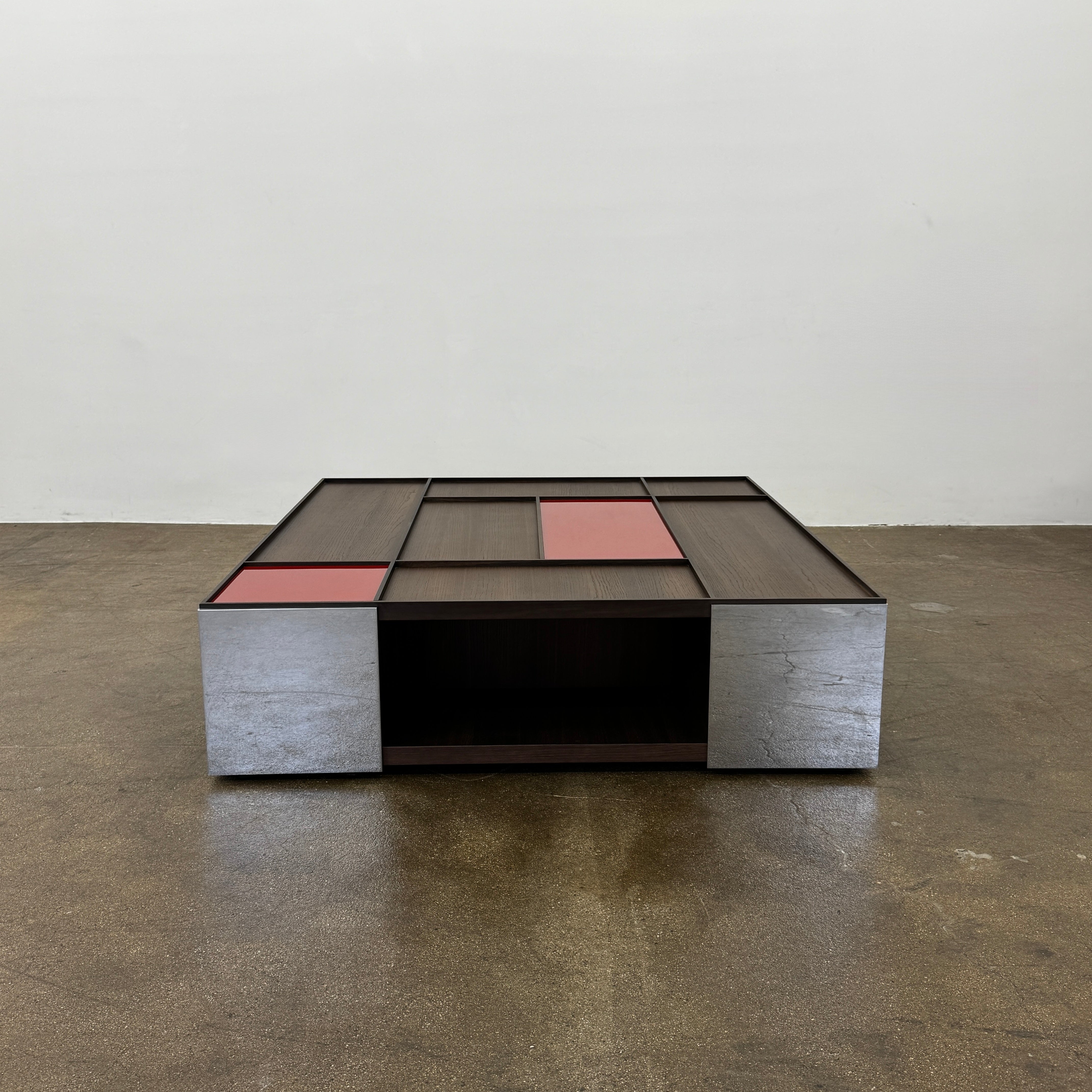 A modern square coffee table by B&B Italia, the Surface Coffee Table features wood, concrete-like panels, and two red rectangular accents—ideal for admirers of geometric designer furniture.