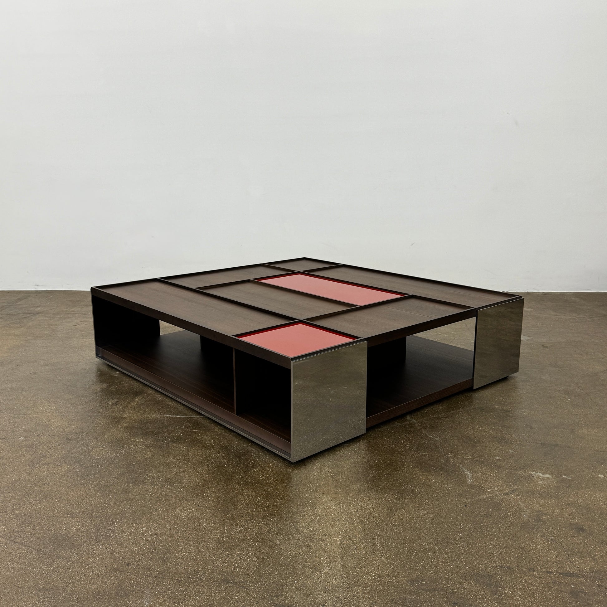 A modern square coffee table by B&B Italia, the Surface Coffee Table features wood, concrete-like panels, and two red rectangular accents—ideal for admirers of geometric designer furniture.