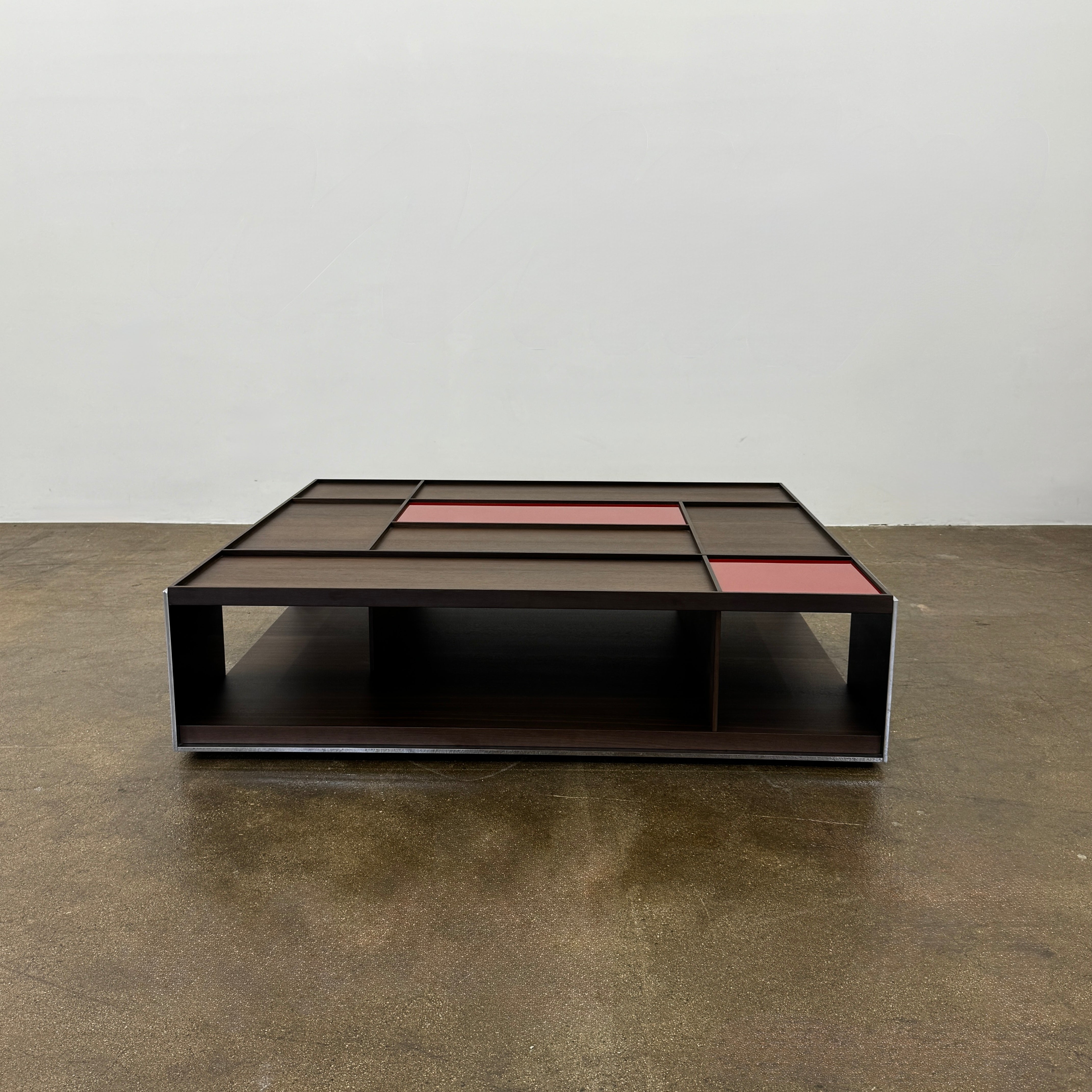 A modern square coffee table by B&B Italia, the Surface Coffee Table features wood, concrete-like panels, and two red rectangular accents—ideal for admirers of geometric designer furniture.