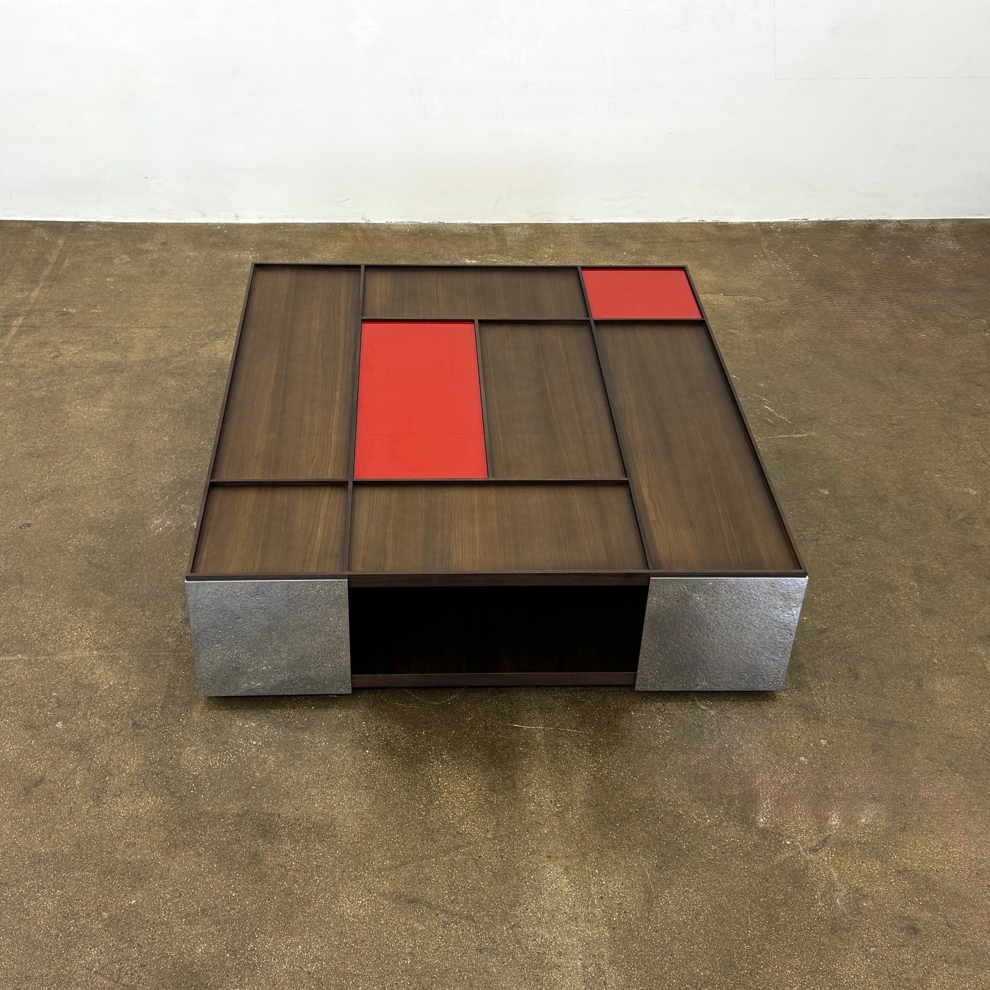 A modern square coffee table by B&B Italia, the Surface Coffee Table features wood, concrete-like panels, and two red rectangular accents—ideal for admirers of geometric designer furniture.